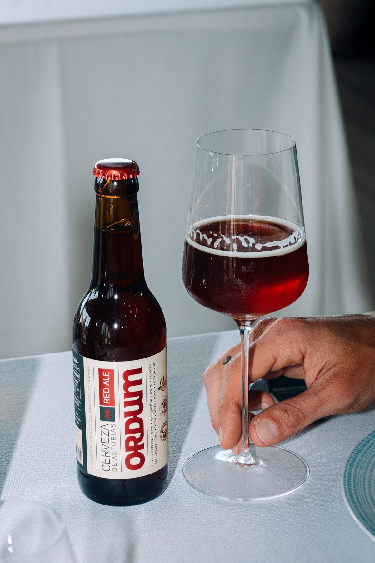 Ayalga x Ordum: botella de Ordum y copa de cerveza en una mesa con mantel blanco