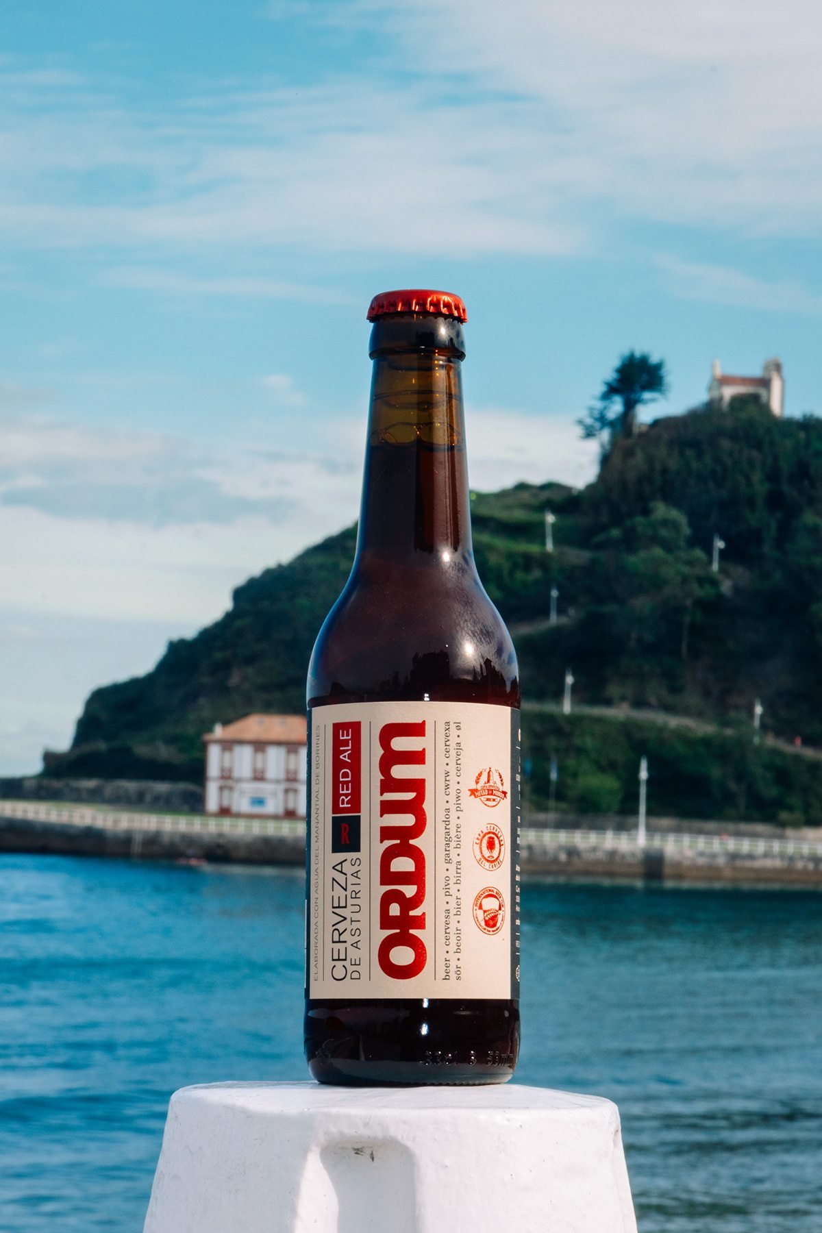 Ayalga x Ordum: botella de Ordum con el mar y la costa al fondo