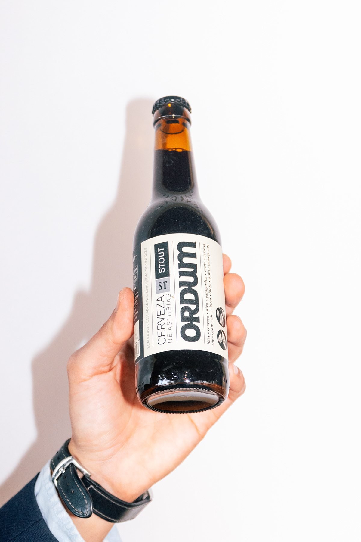 Ayalga x Ordum: mano sosteniendo una botella de Ordum sobre fondo blanco