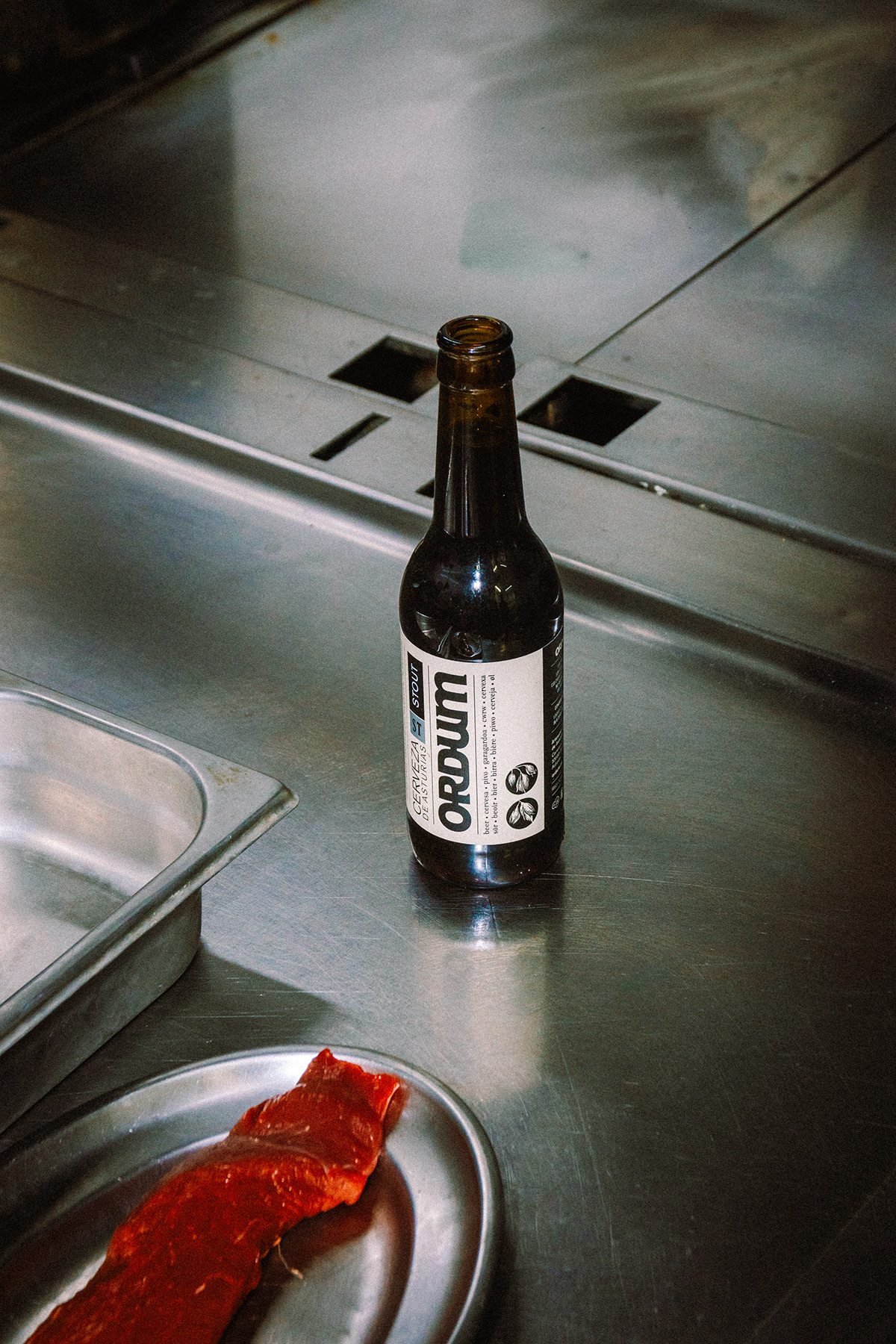 Ayalga x Ordum: botella de Ordum junto a una pieza de carne cruda en la cocina