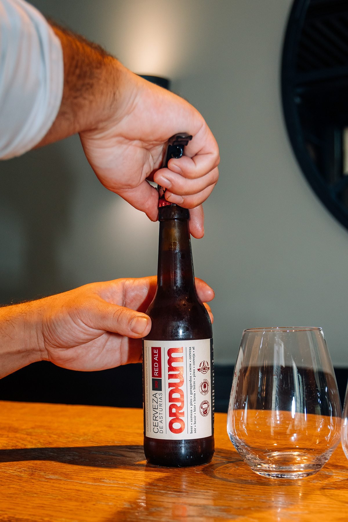 Ayalga x Ordum: manos abriendo una botella de Ordum junto a una copa vacía