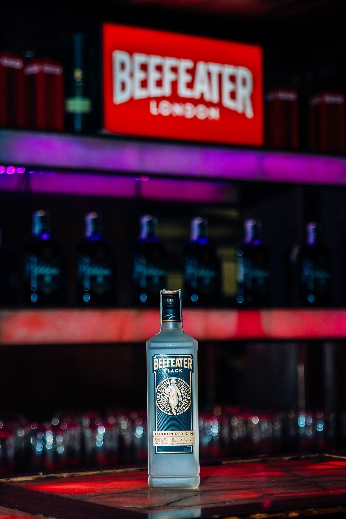 Beefeater London: botella sobre la barra iluminada con el letrero de la marca al fondo
