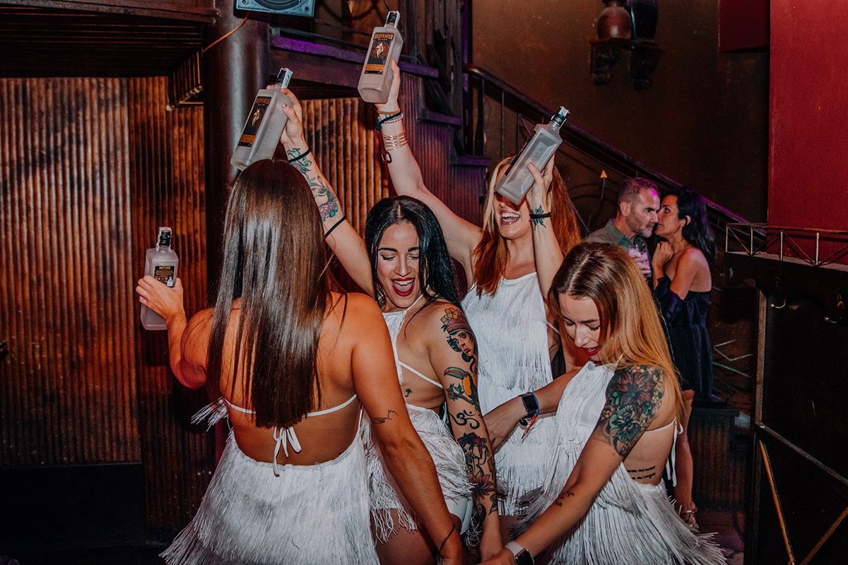 Beefeater London: grupo de mujeres con vestidos blancos bailando con botellas en alto