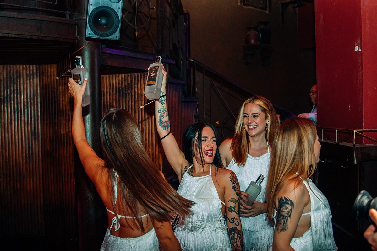 Beefeater London: mujeres con vestidos blancos de flecos alzando botellas en la fiesta