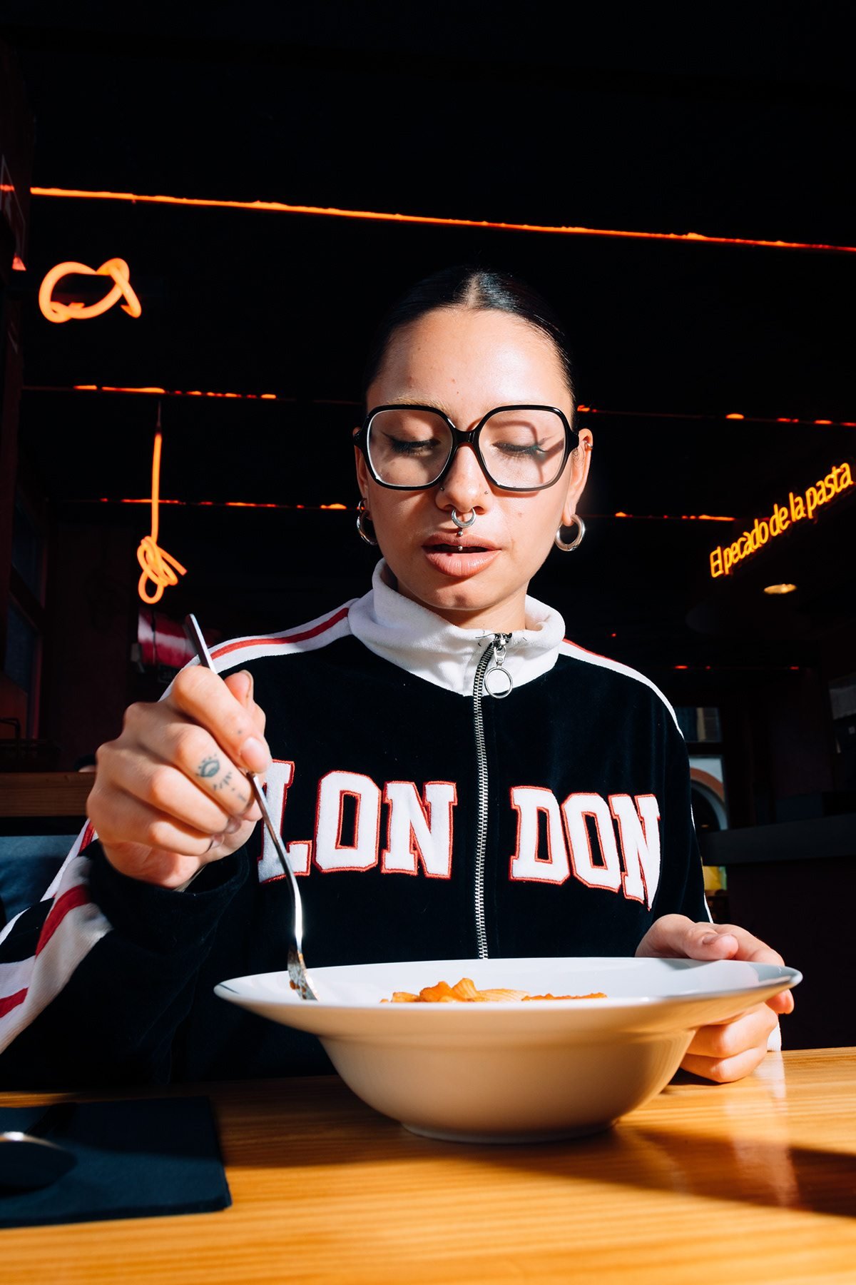 Gula: mujer con gafas comiendo pasta de un plato en una mesa