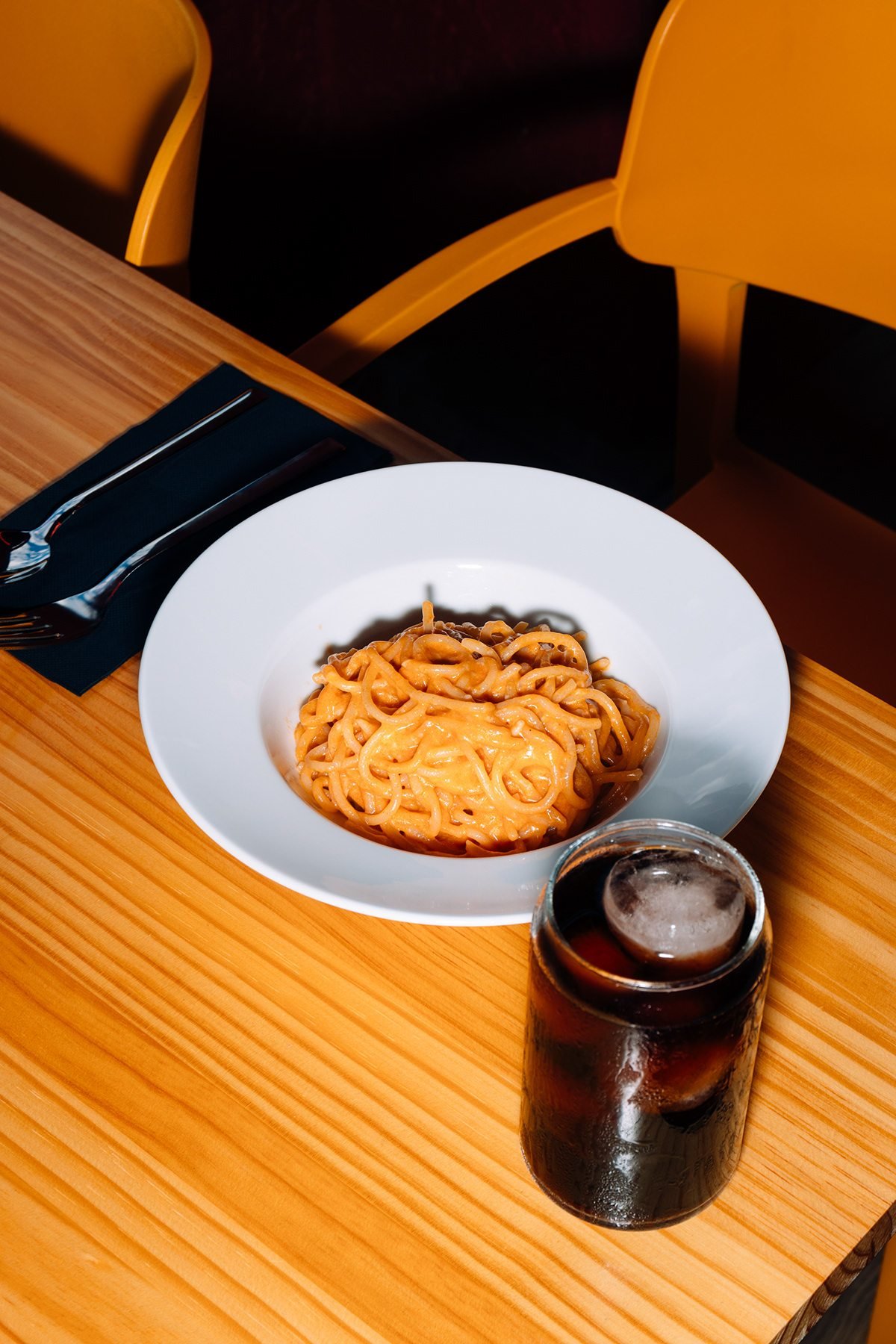 Gula: plato de pasta con salsa de tomate y una bebida en una mesa de madera