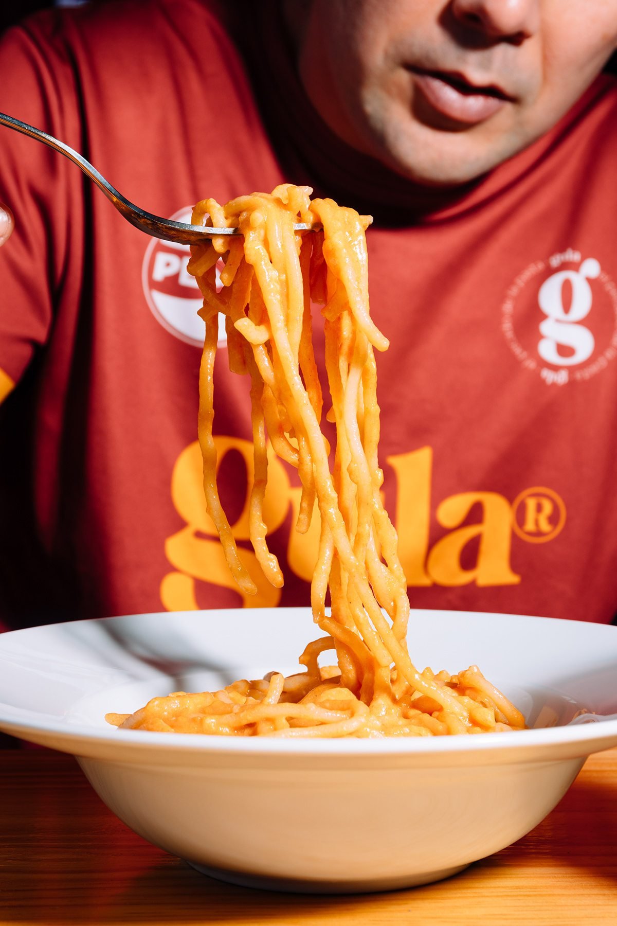 Gula: hombre con camiseta de Gula levantando pasta con un tenedor