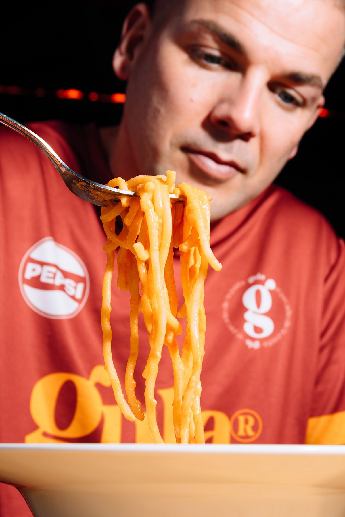 Gula: hombre con camiseta de Gula mirando la pasta enrollada en su tenedor