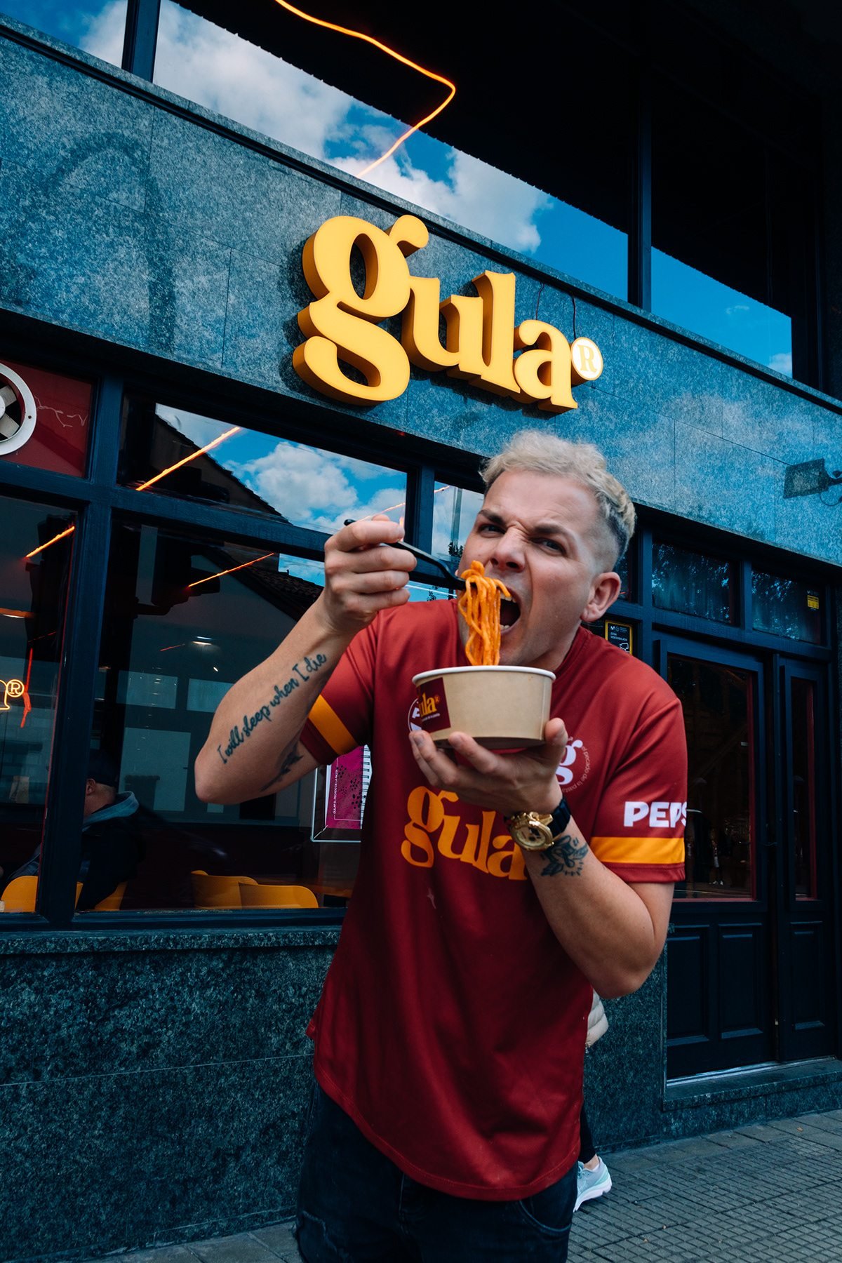 Gula: hombre comiendo pasta de un bol frente al local de Gula
