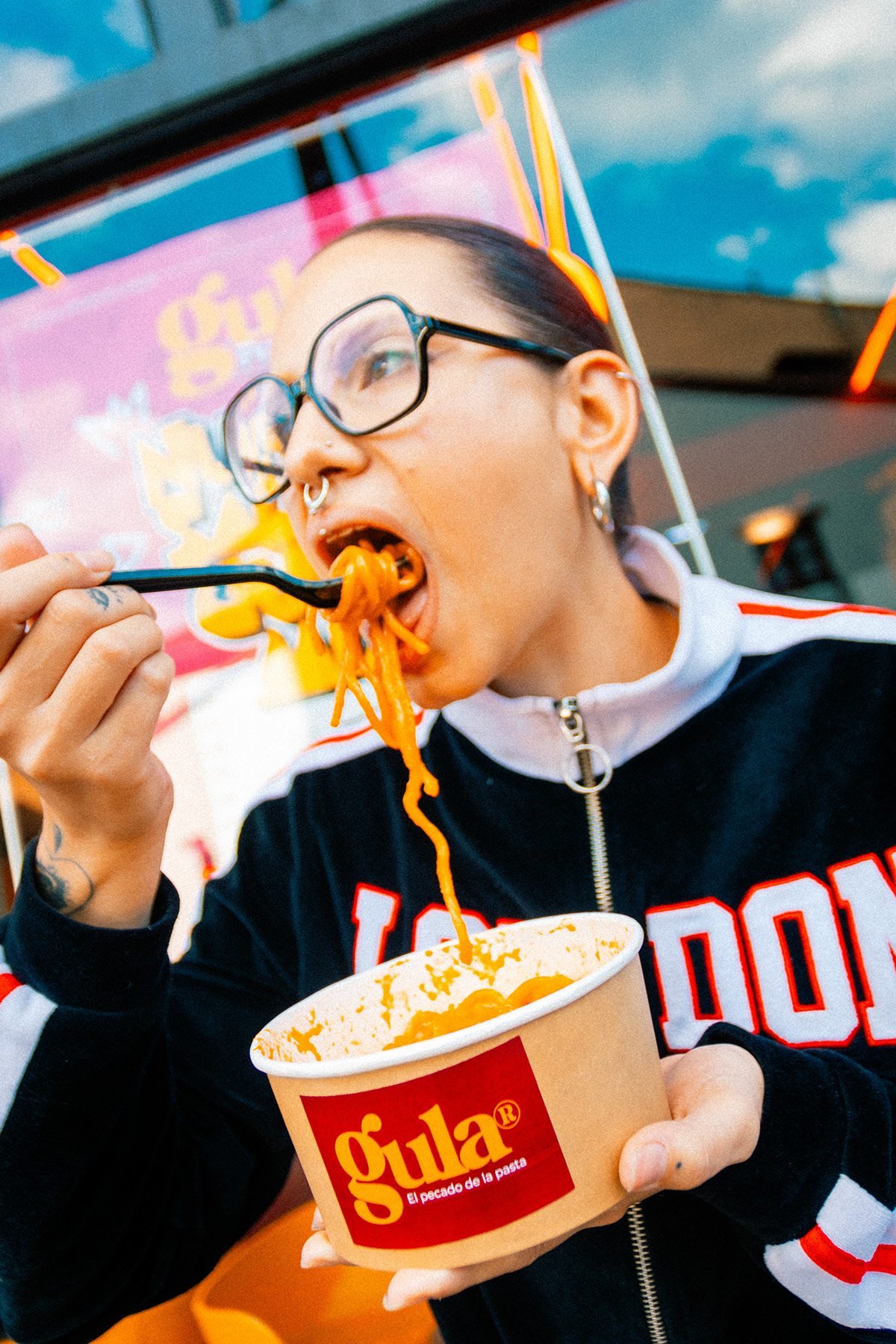 Gula: mujer con gafas comiendo pasta de un bol de Gula al aire libre