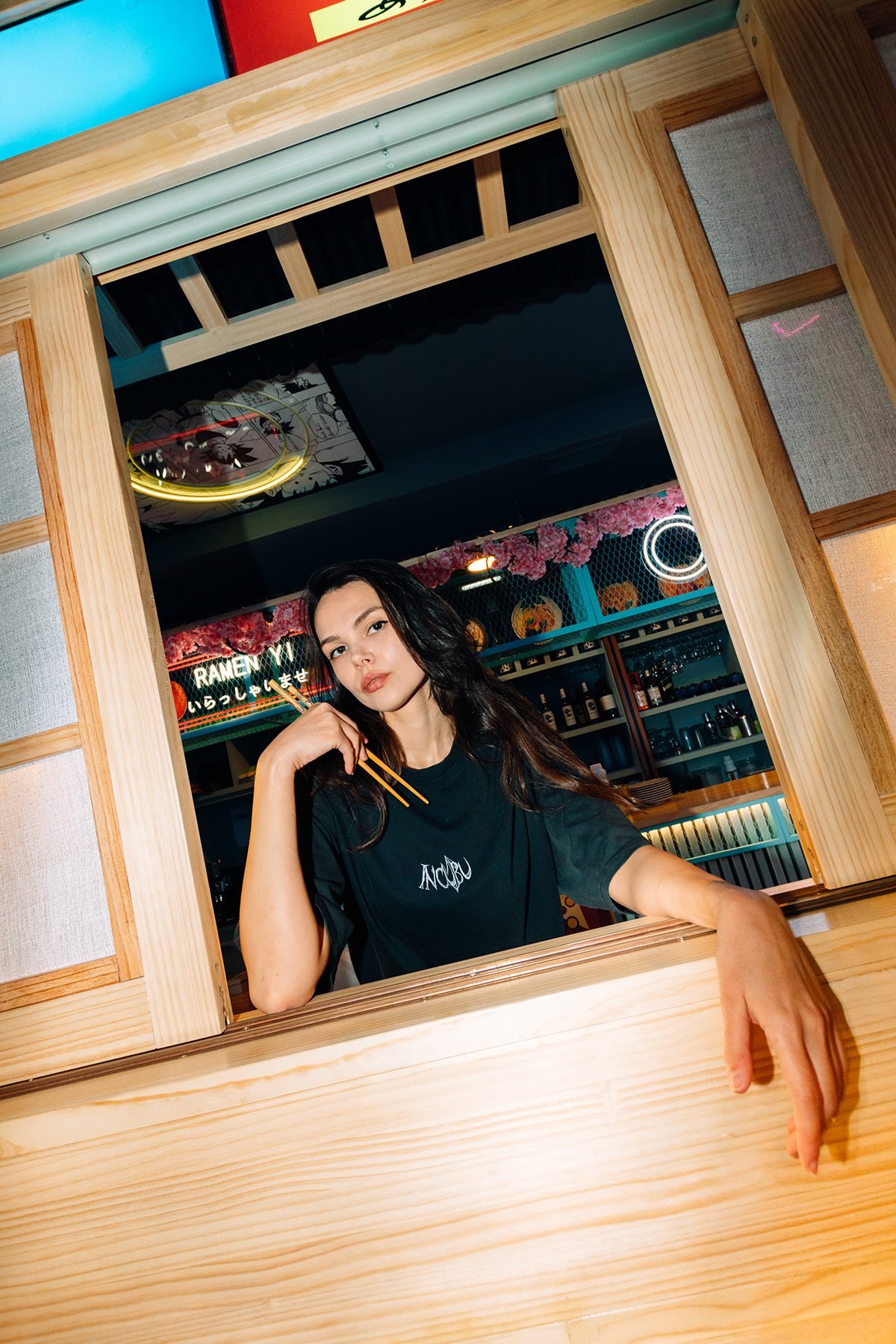Incubu Clothing: modelo con camiseta negra asomada a una ventana de madera