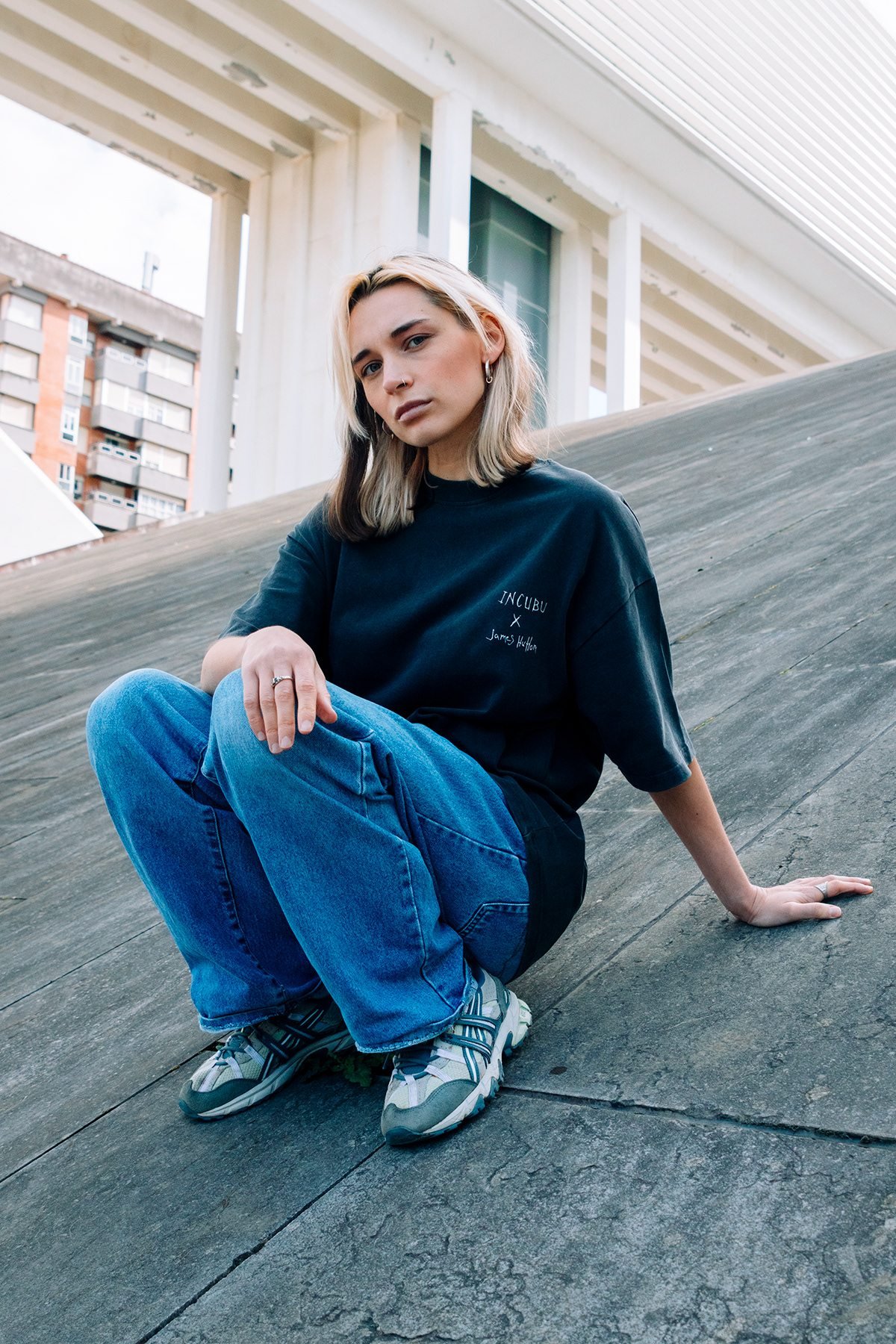 Incubu Clothing: modelo con camiseta negra sentada sobre una rampa de hormigón