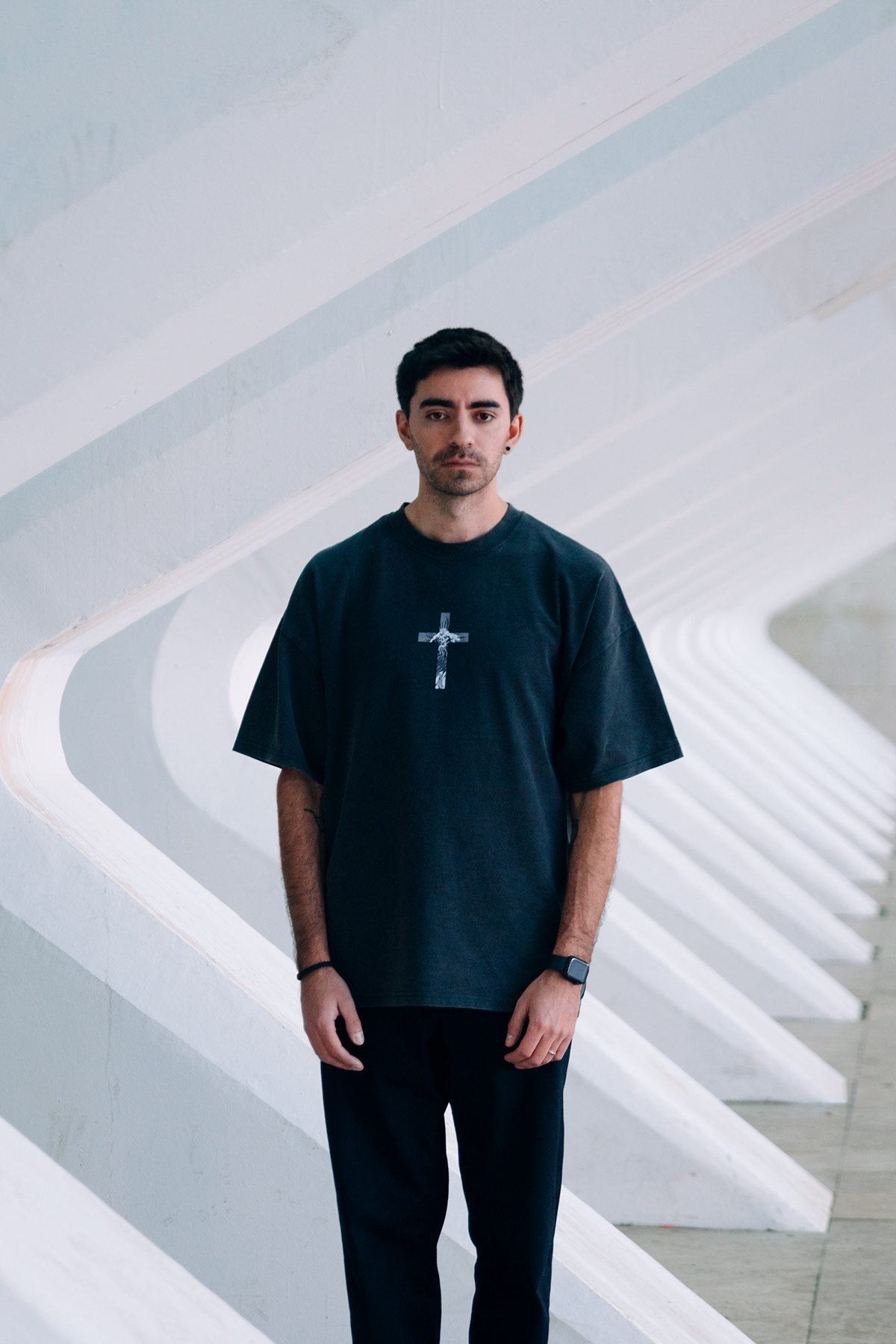 Incubu Clothing: modelo con camiseta negra con una cruz estampada entre arcos blancos