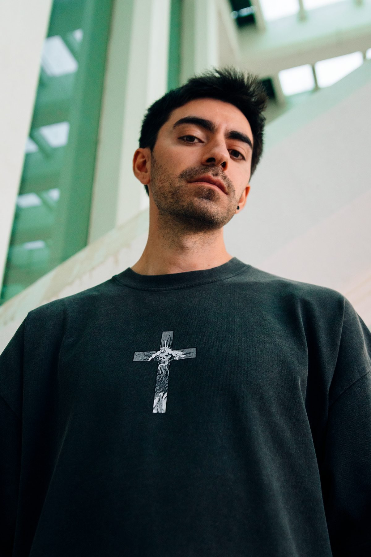 Incubu Clothing: modelo con camiseta con una cruz estampada, en contrapicado