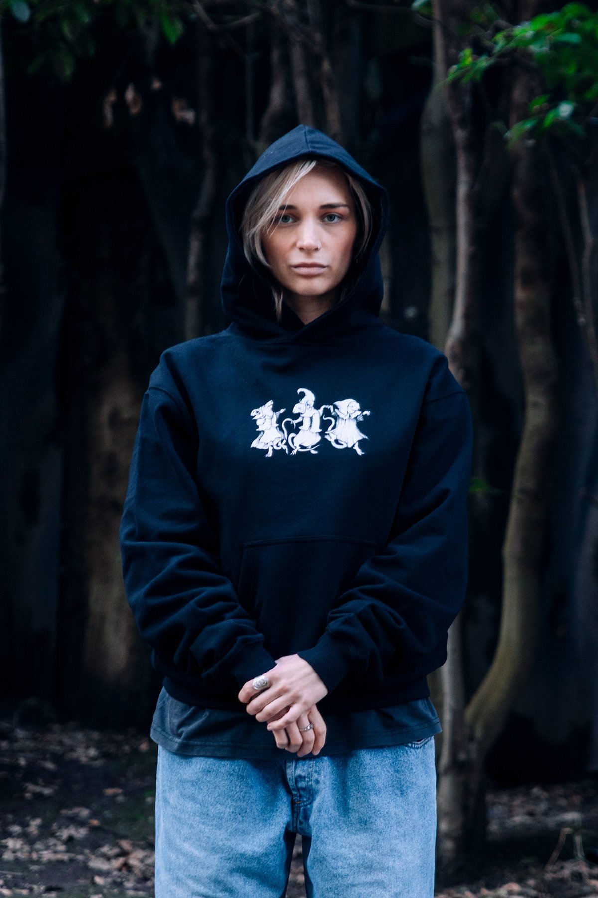 Incubu Clothing: modelo con sudadera negra con capucha estampada entre árboles