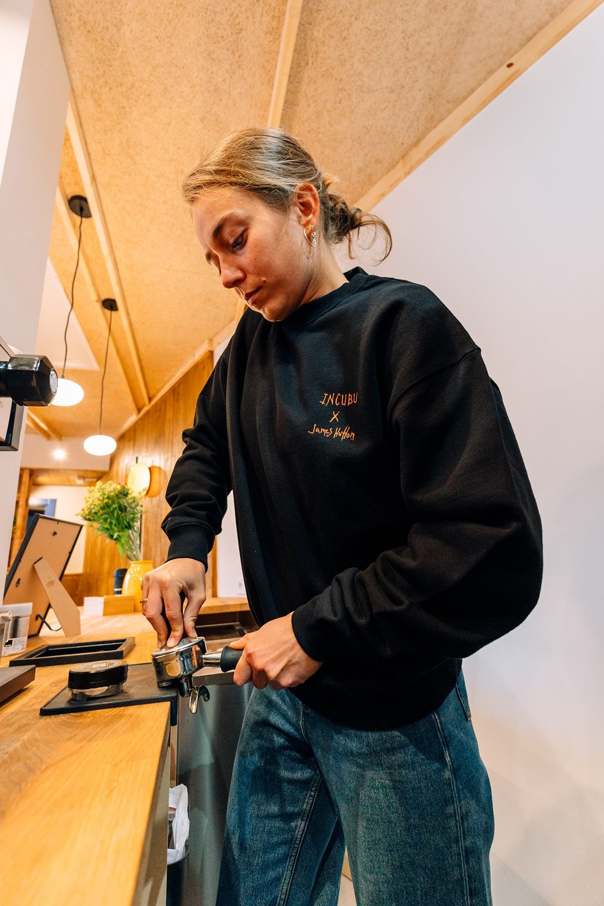 Incubu Clothing: modelo con sudadera negra en la barra de una cafetería