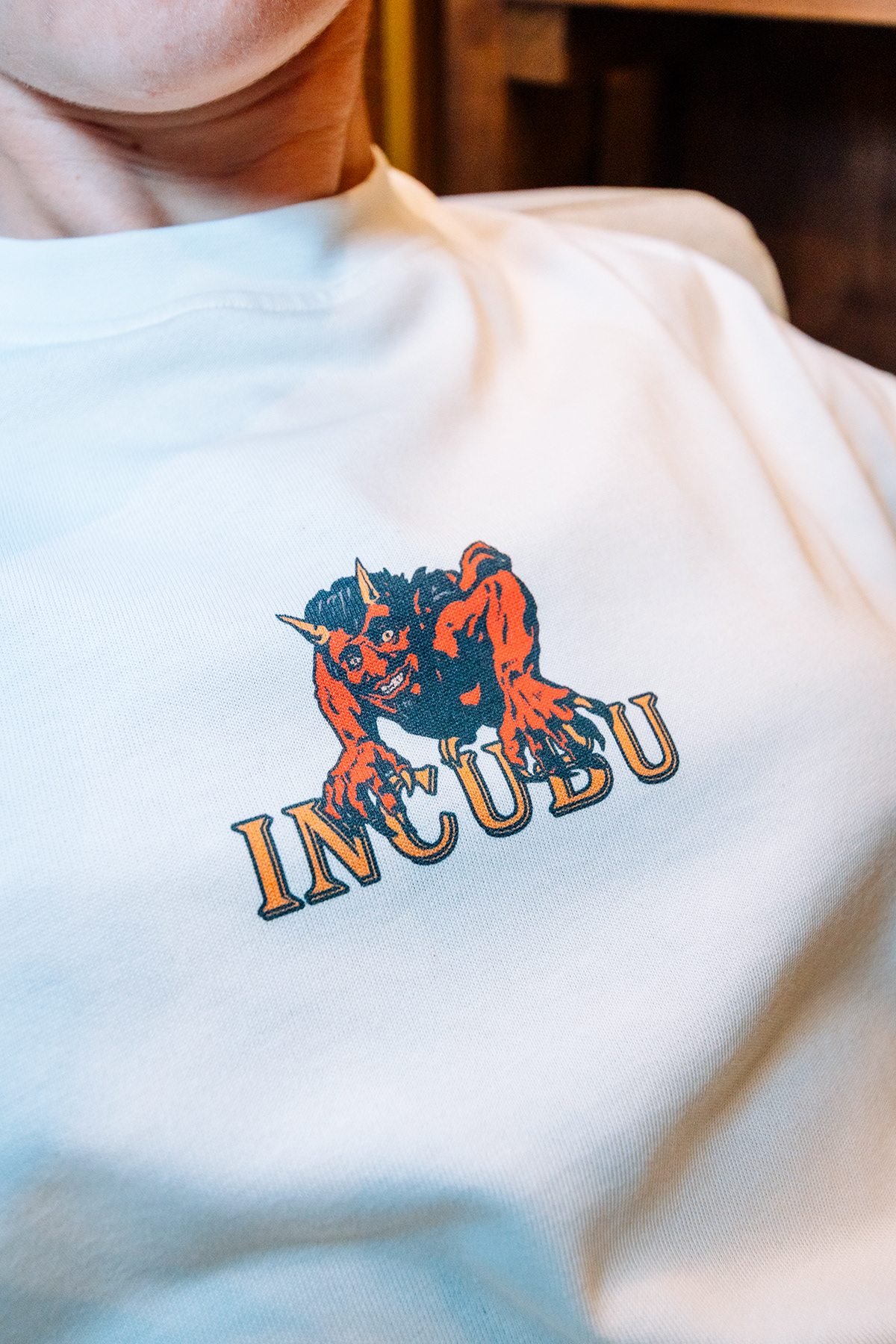 Incubu Clothing: detalle del logotipo estampado en una camiseta blanca