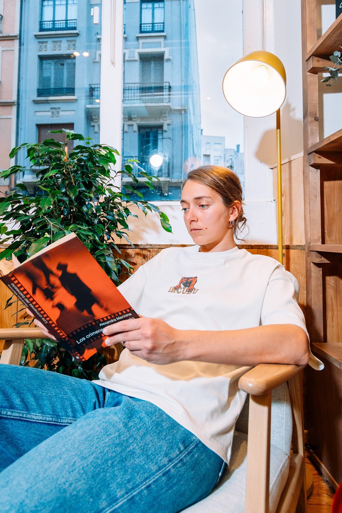 Incubu Clothing: modelo con camiseta blanca leyendo un libro en un sillón