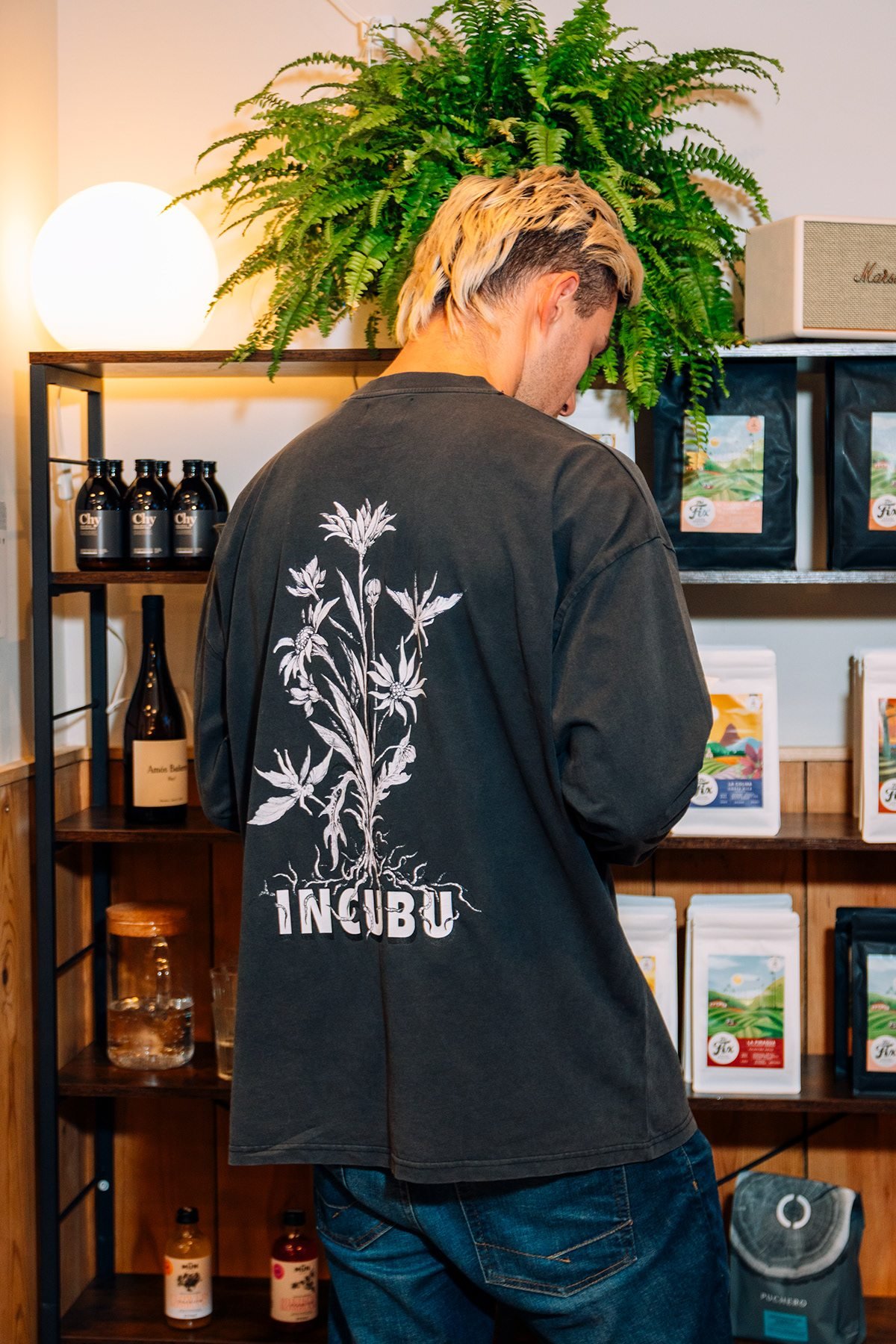 Incubu Clothing: modelo de espaldas con sudadera estampada junto a una estantería