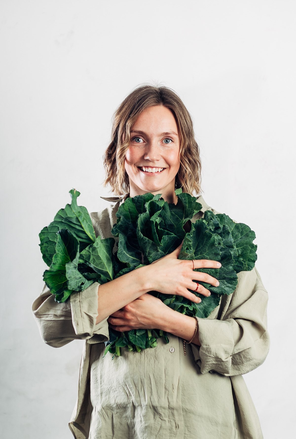 Vilma: mujer sonriente abrazando un manojo de verduras de hoja verde