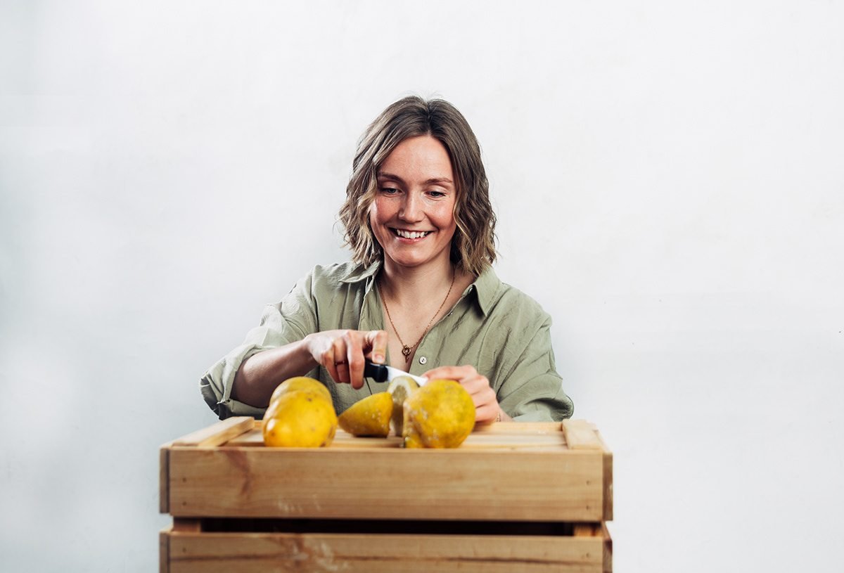 Vilma: mujer cortando limones sobre una caja de madera, plano general
