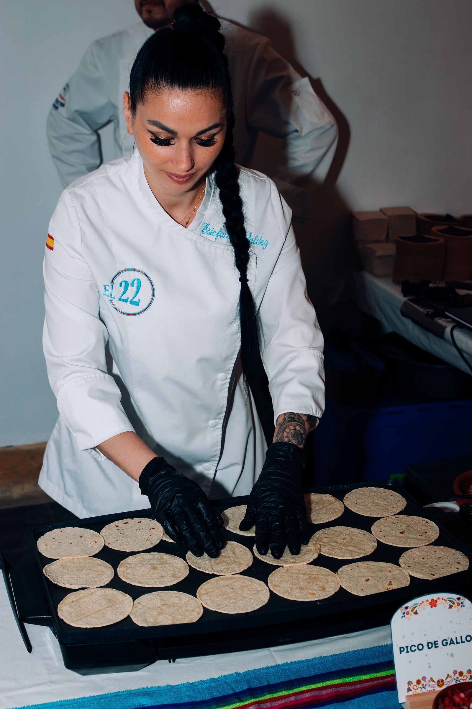 Cocinera prepara varios platos sobre la mesa de trabajo.