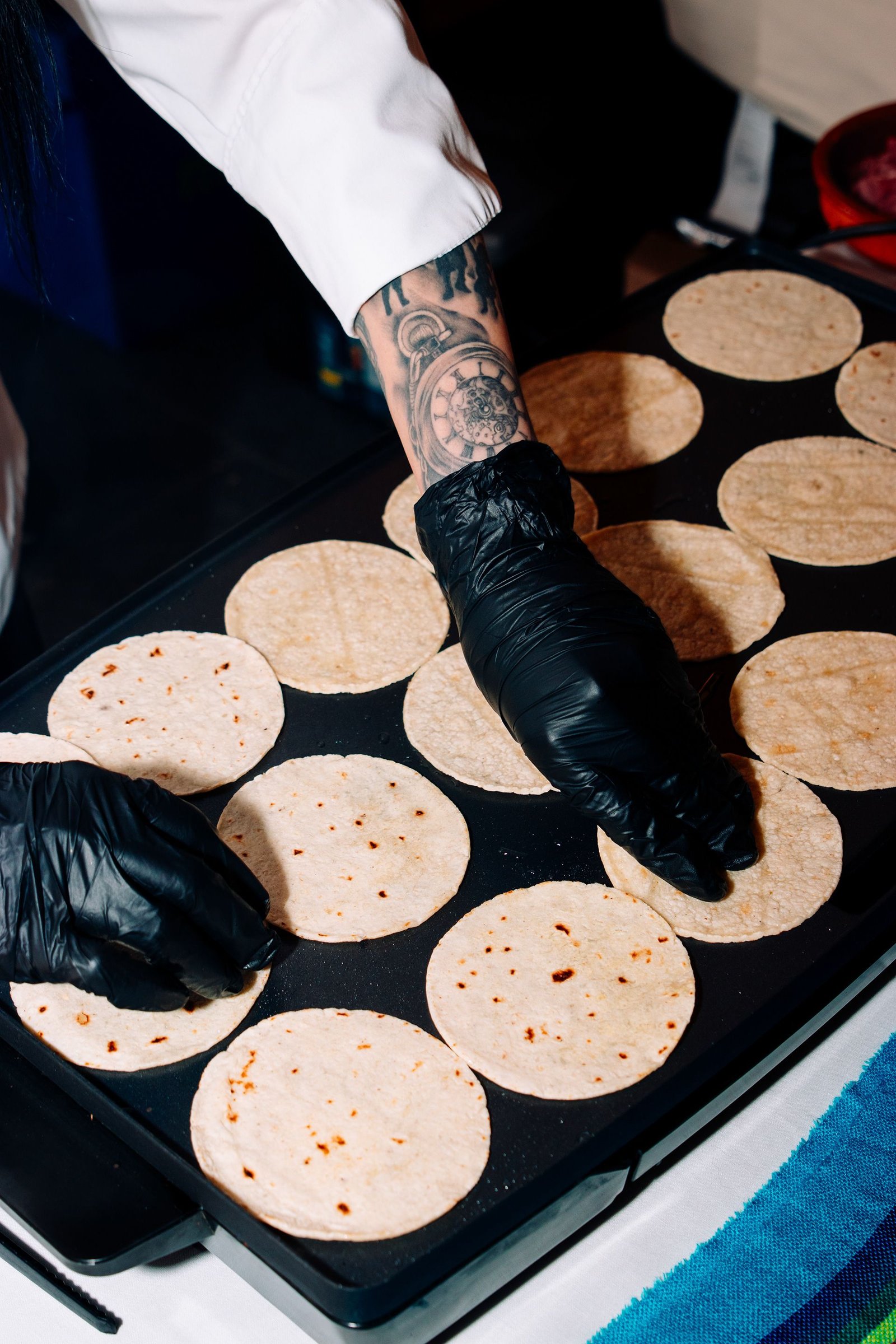 Mano enguantada añade ingredientes a una sartén.