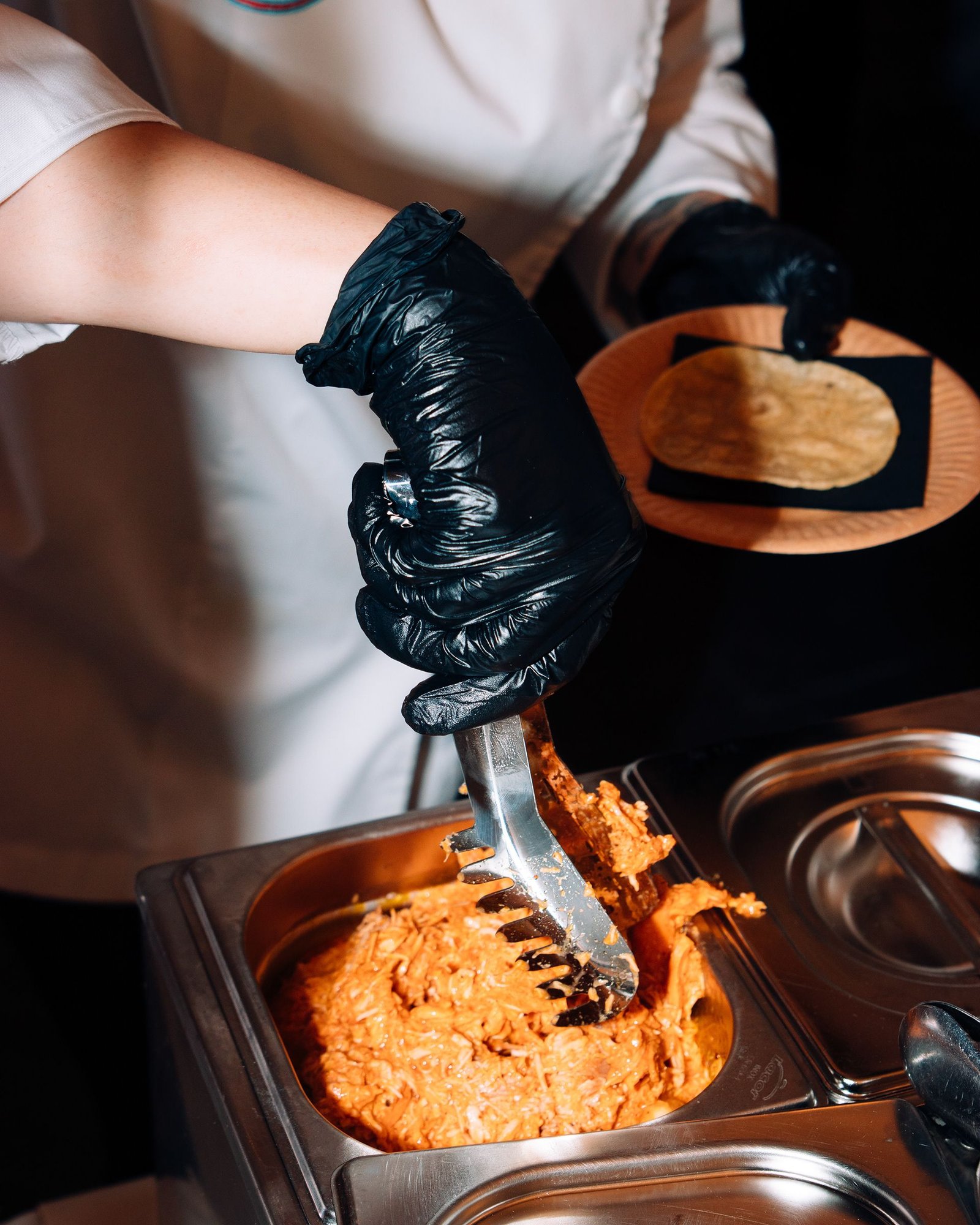 Manos sirven una preparación de color naranja en una cazuela.