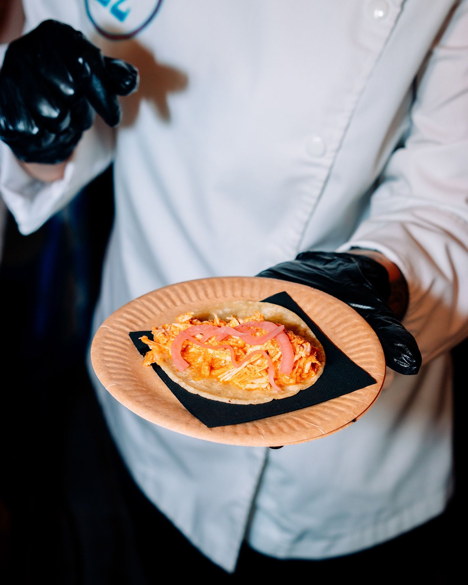 Cocinero presenta un plato junto a la mesa de cocina.