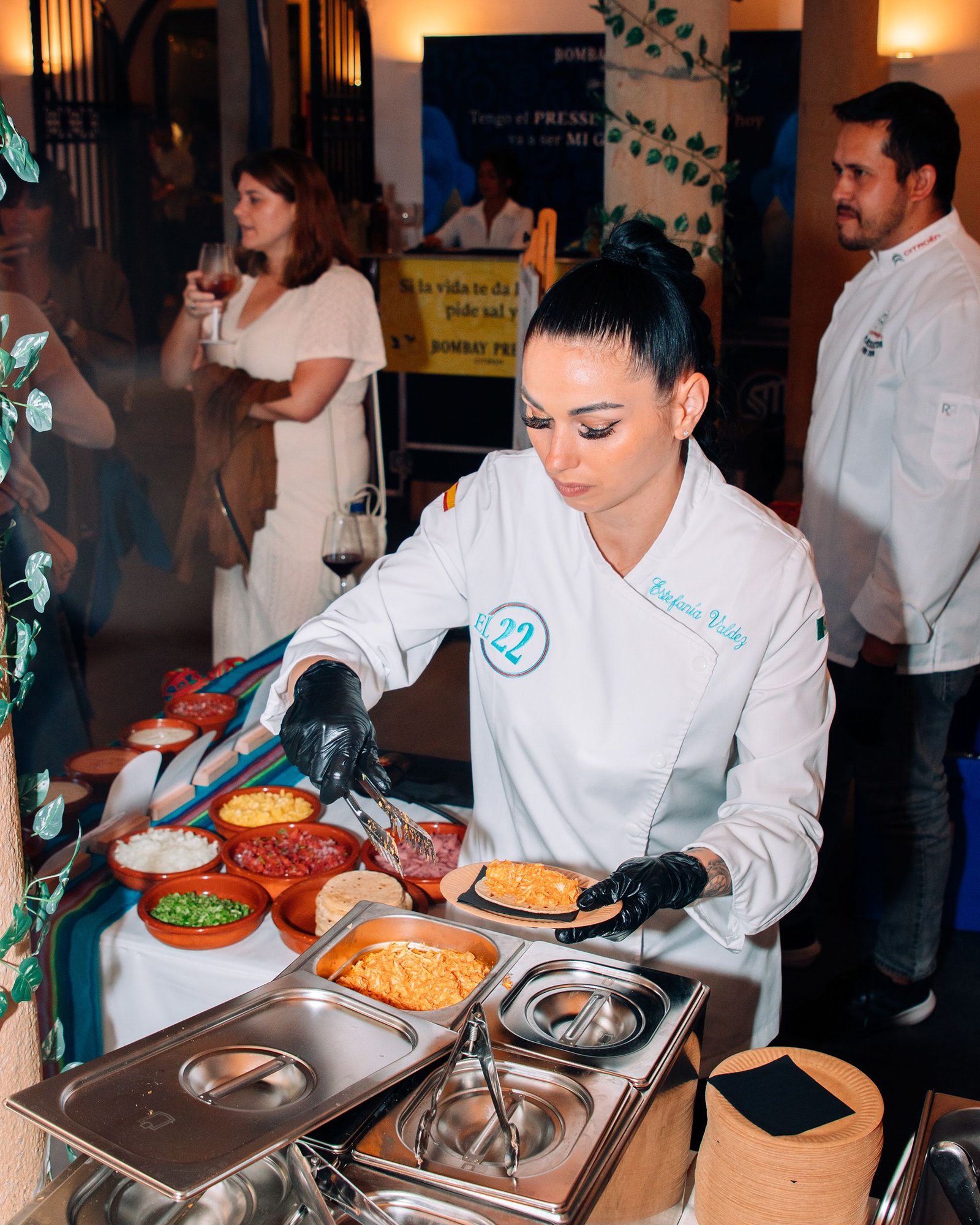 Dos profesionales preparan comida en una mesa de trabajo.
