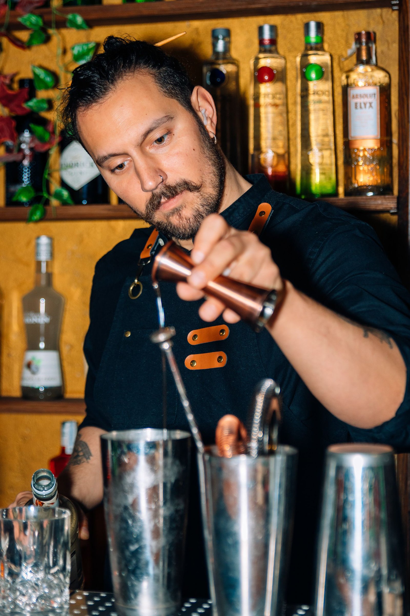 Barista inclinado sobre la barra durante la preparación de un cóctel.