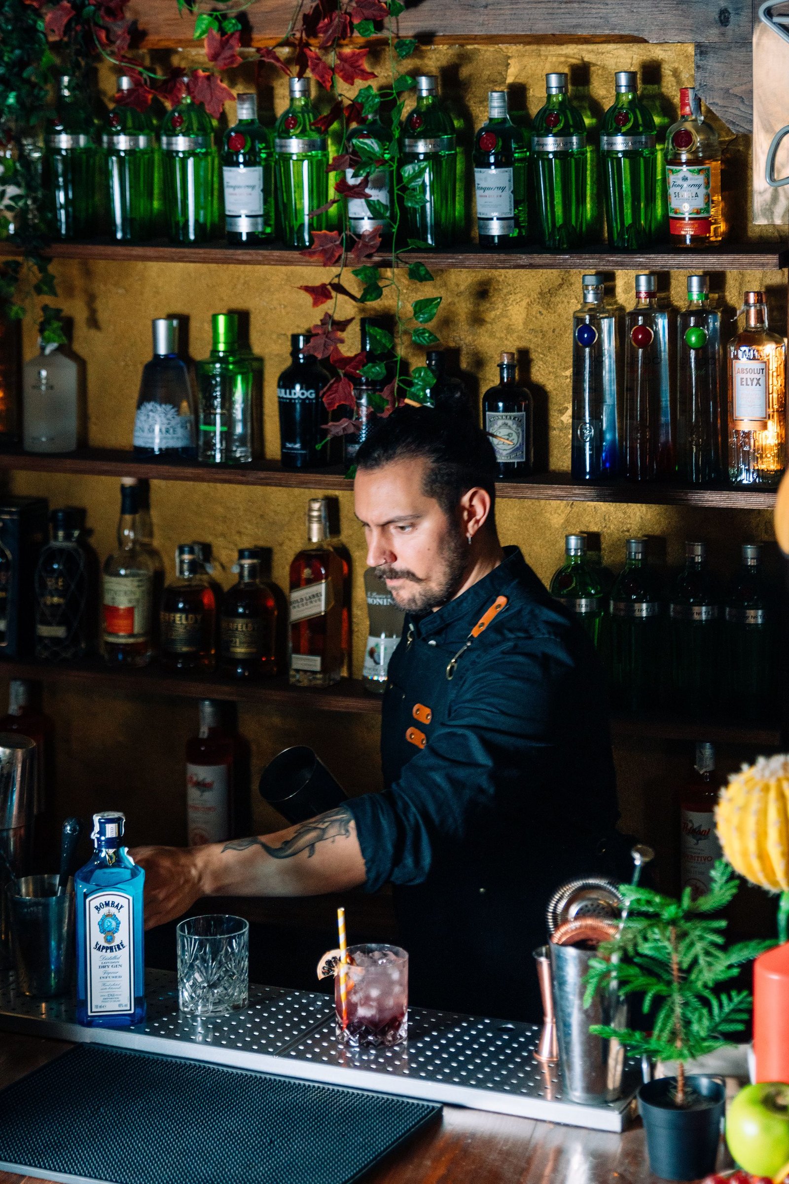 Manos preparan una bebida con ingredientes y utensilios de coctelería.