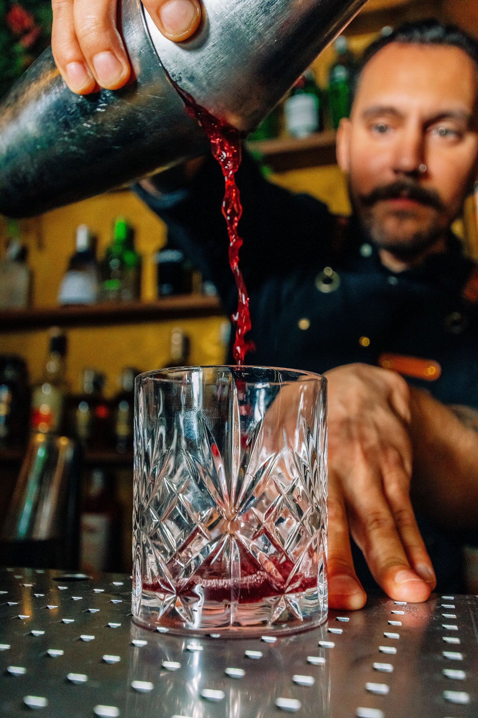 Barista vierte una bebida desde una botella sobre el vaso.