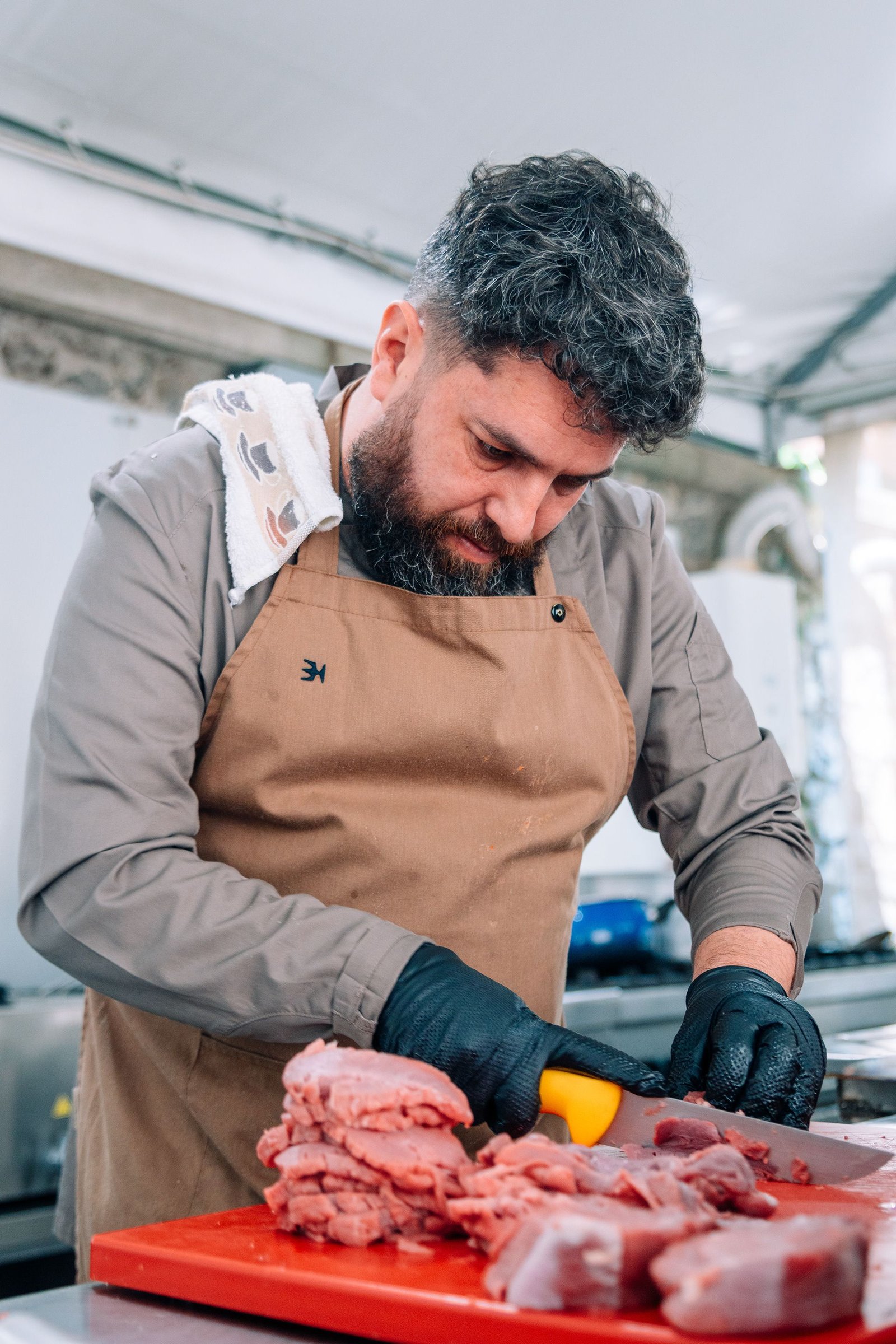 Cocinero con delantal prepara carne sobre una tabla.