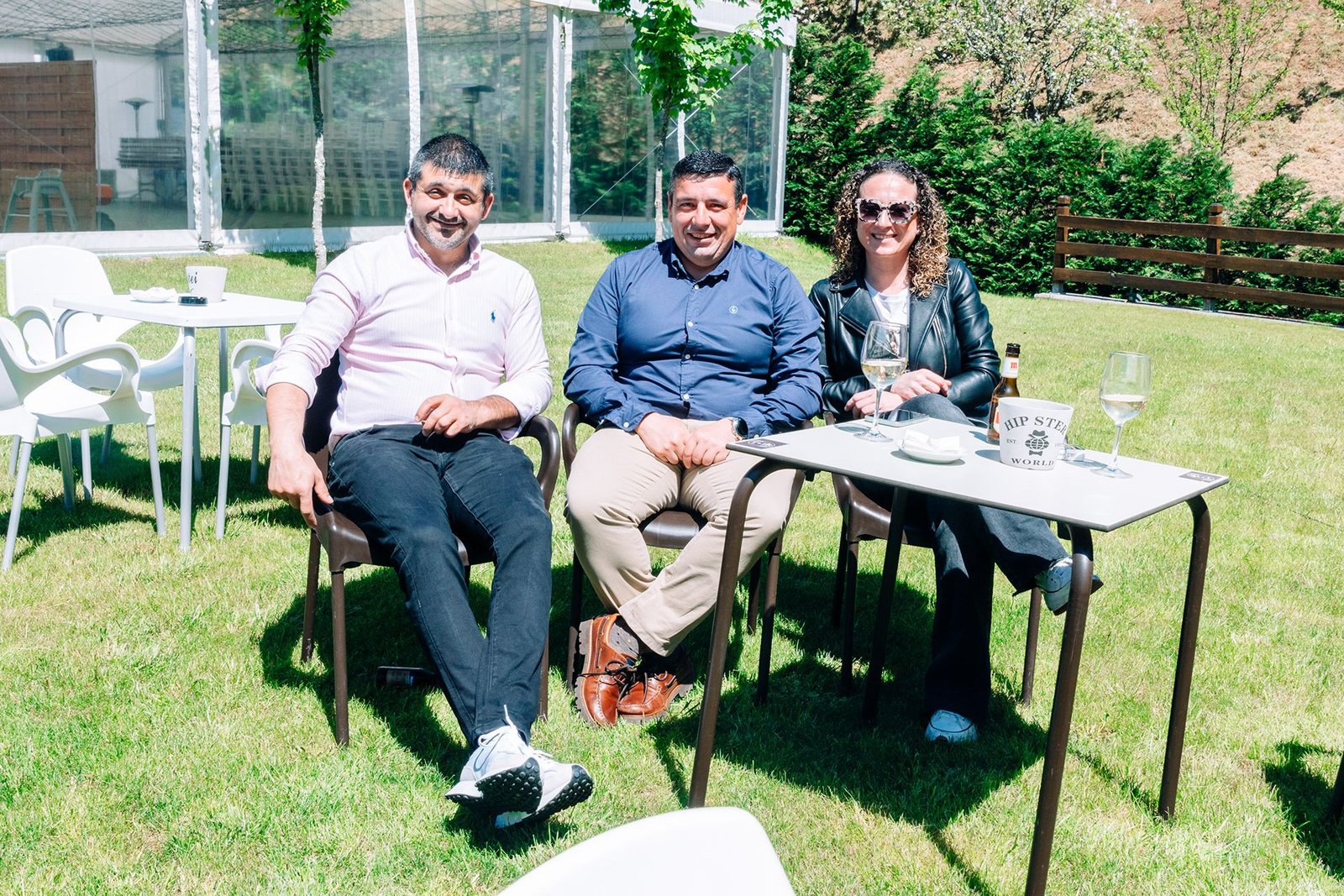 Grupo de personas conversa alrededor de una mesa en el jardín.