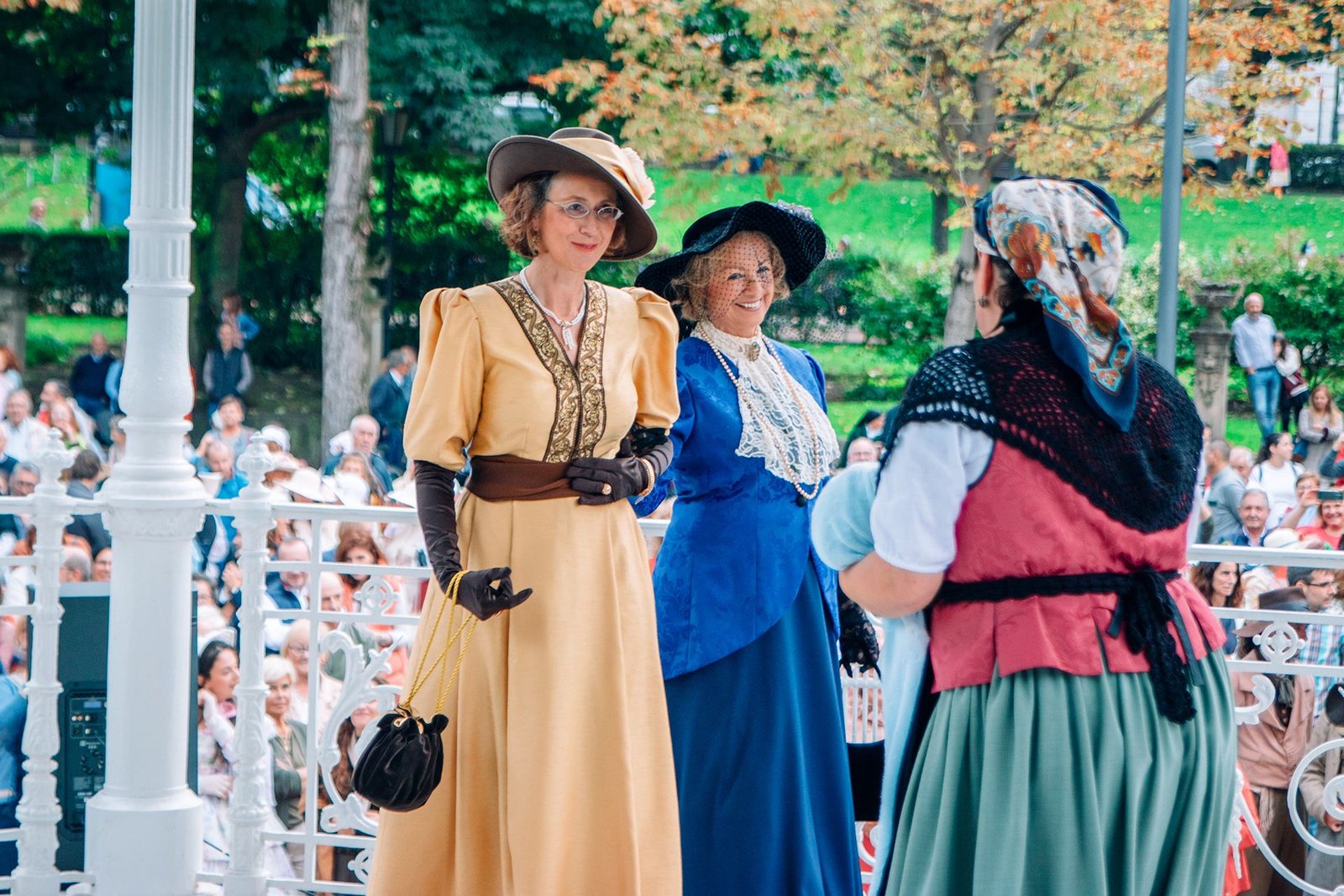 Mujeres con trajes tradicionales conversan durante el desfile.