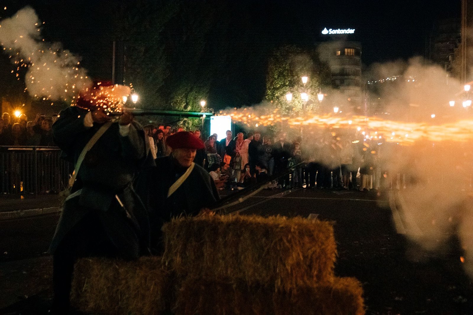 Destellos de pirotecnia iluminan la calle durante la fiesta.