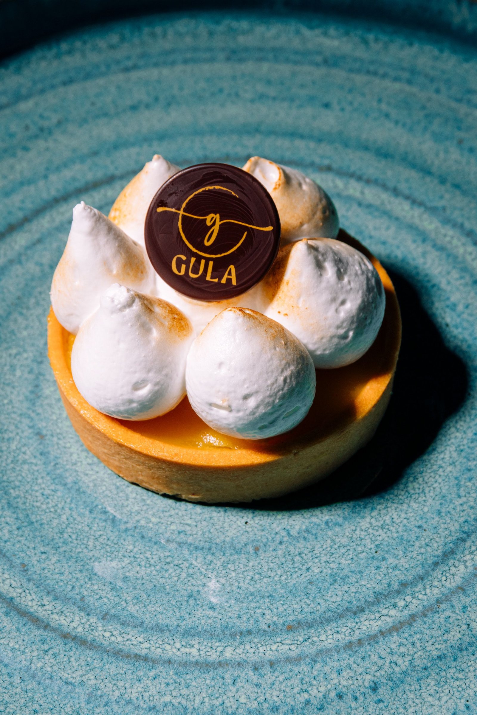 Pequeño pastel redondo con crema blanca y una etiqueta.
