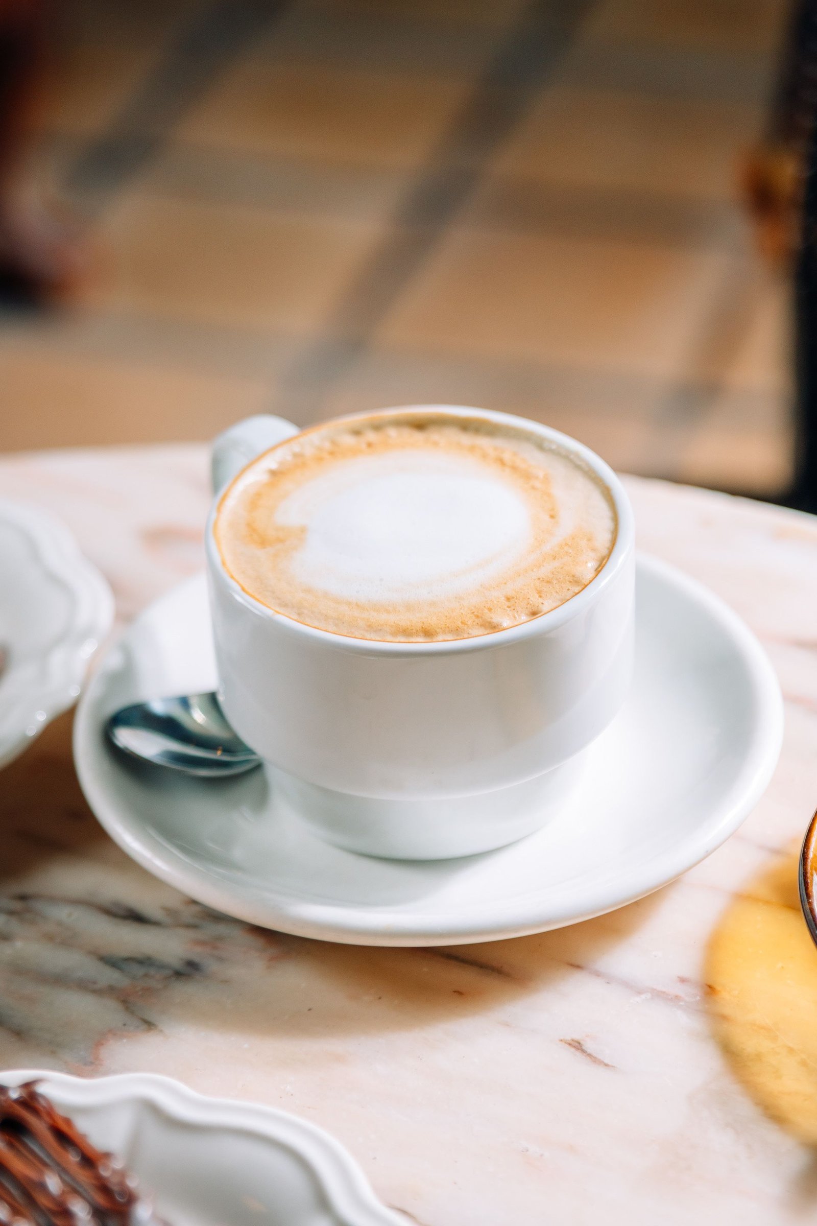 Café con leche en una taza blanca sobre el plato.