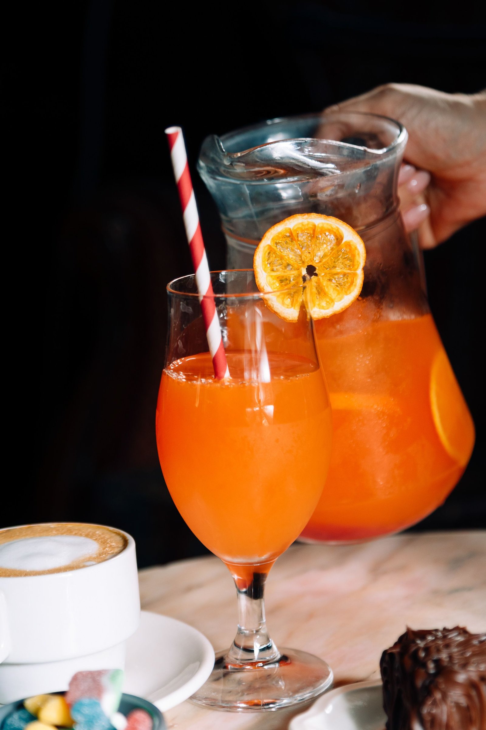Copa de cóctel naranja junto a una bebida con hielo.