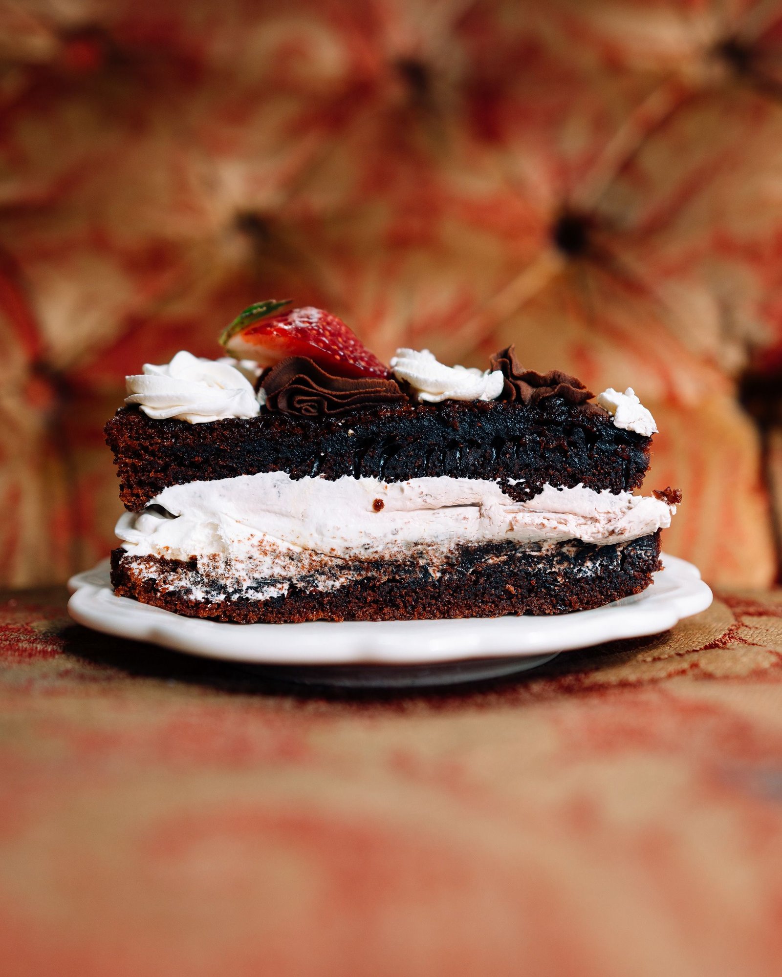 Porción de pastel de chocolate con una capa blanca en el interior.