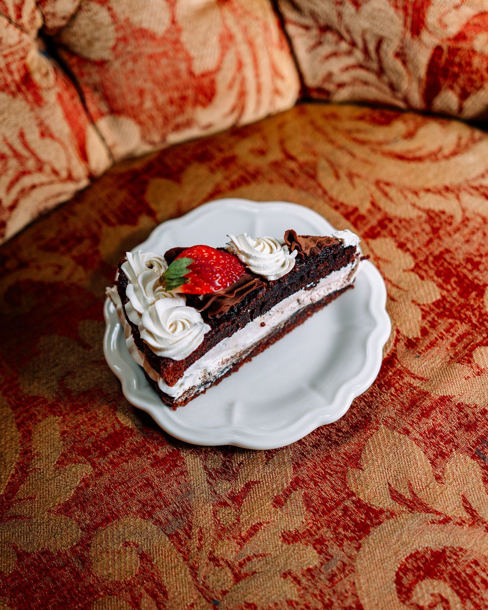 Postre individual de chocolate decorado con una fruta roja.