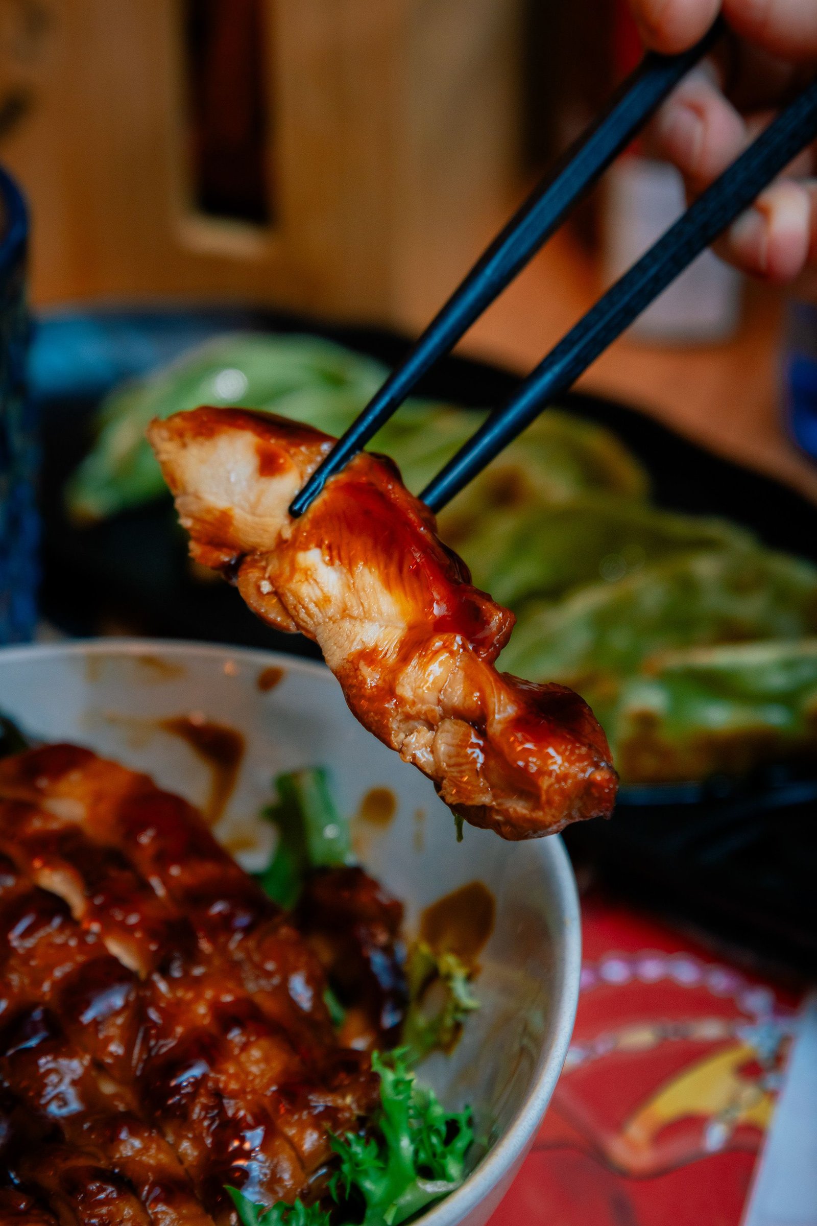 Pieza de pollo rebozado sostenida con palillos.