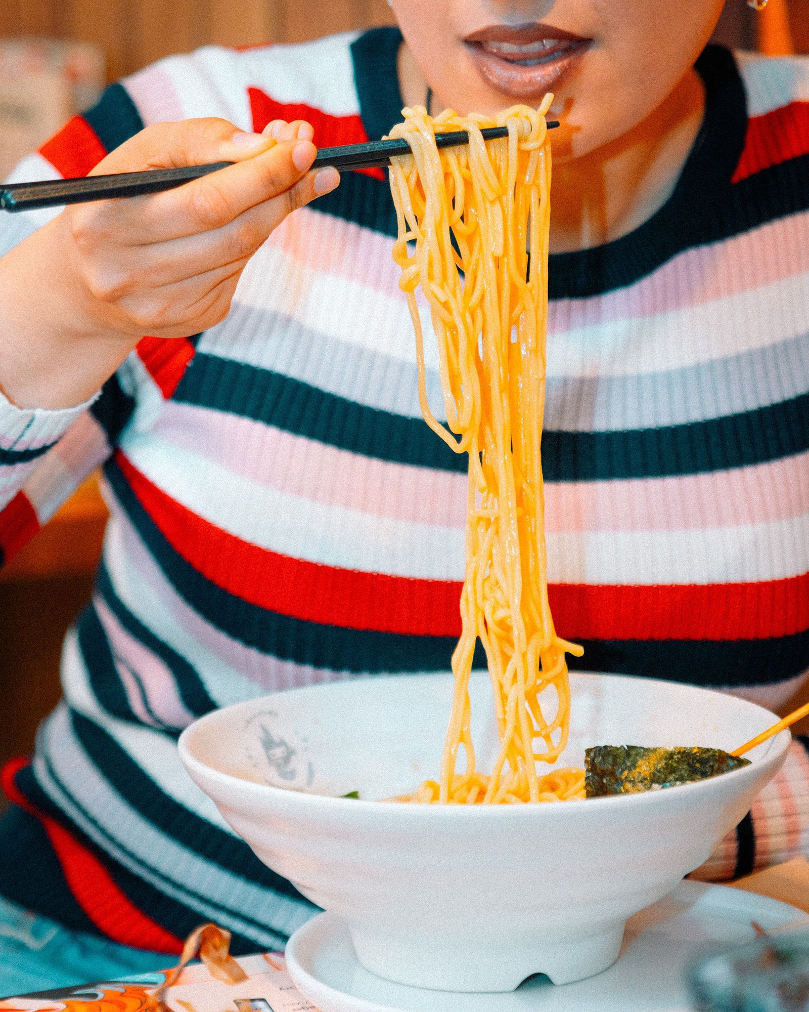Persona sostiene un bowl de ramen sobre un delantal.