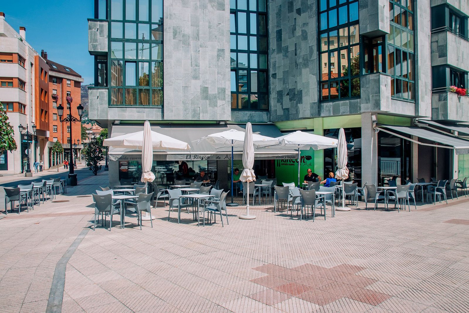 Terraza de restaurante con mesas junto a una calle peatonal.