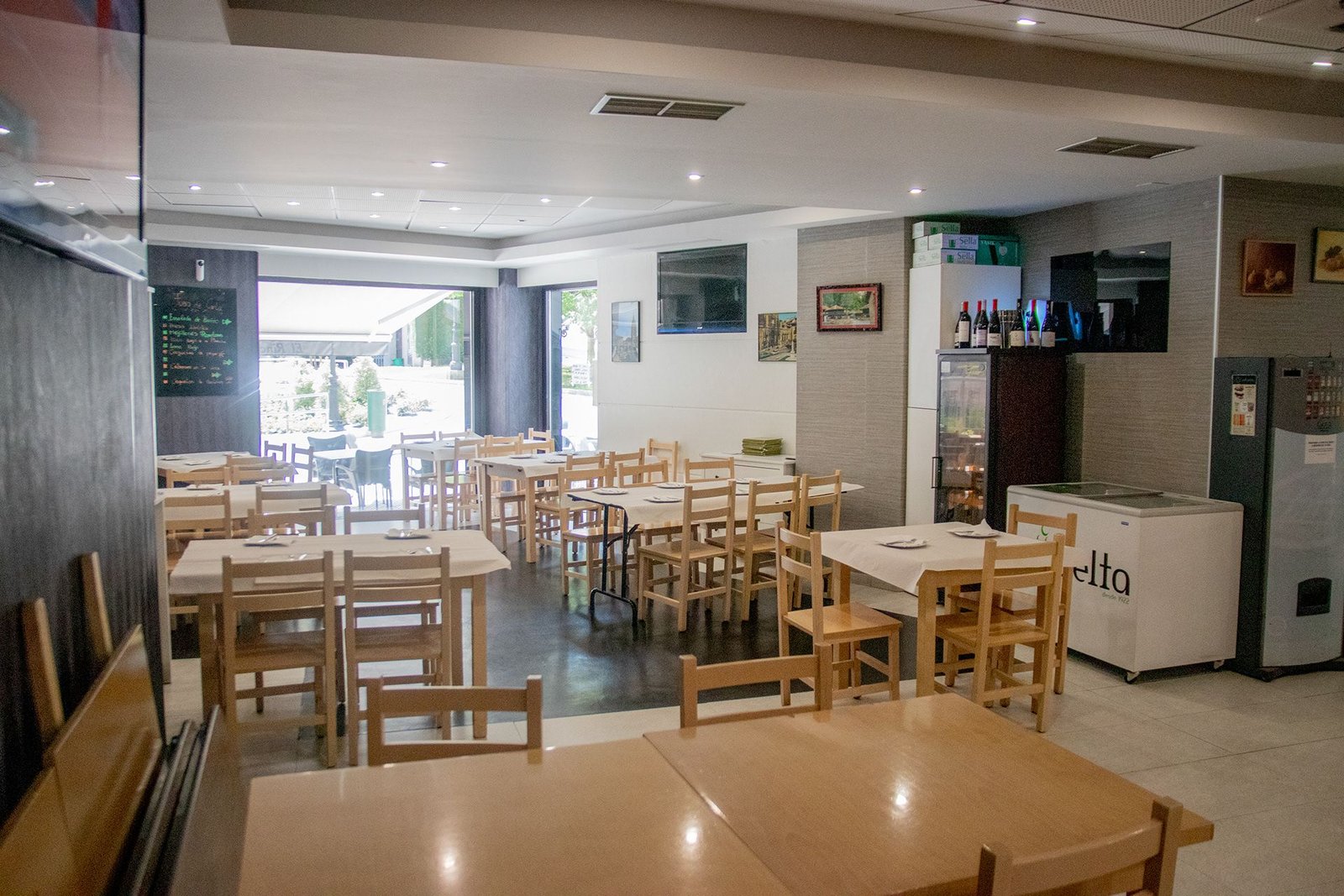 Comedor interior con mesas de madera y sillas preparadas.