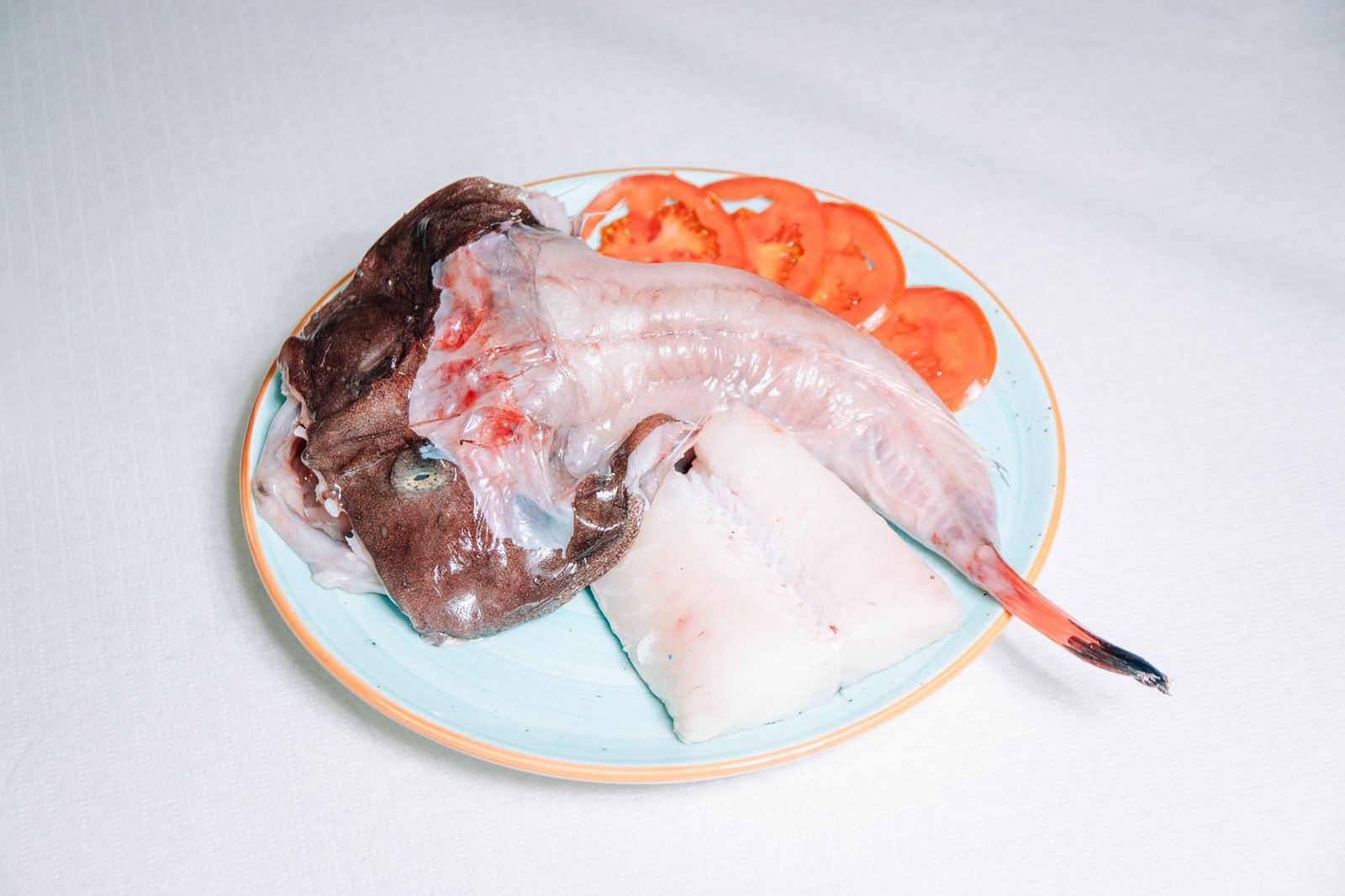 Pescado blanco con guarnición servido en un plato.
