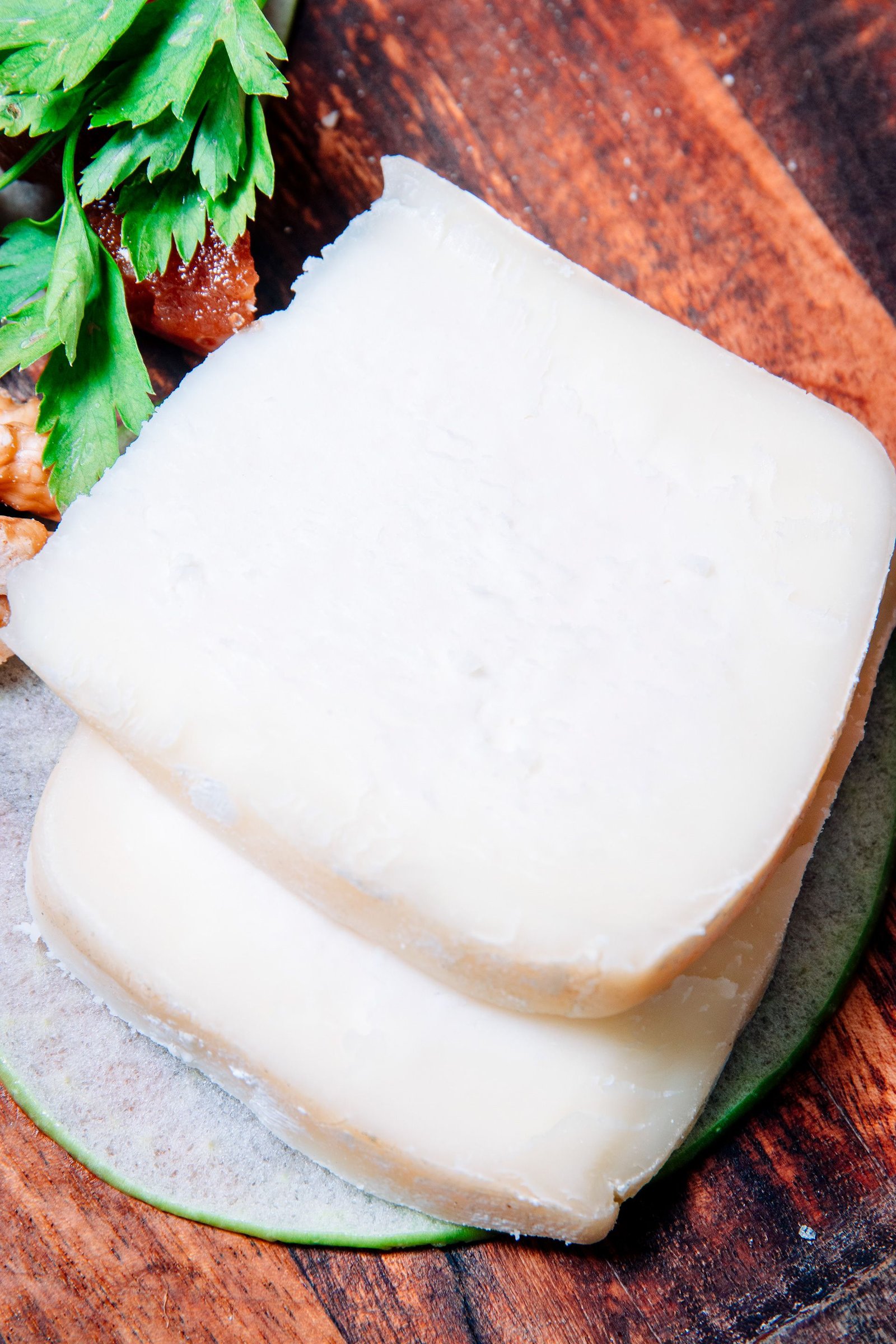 Cuadro de queso blanco servido sobre una hoja verde.