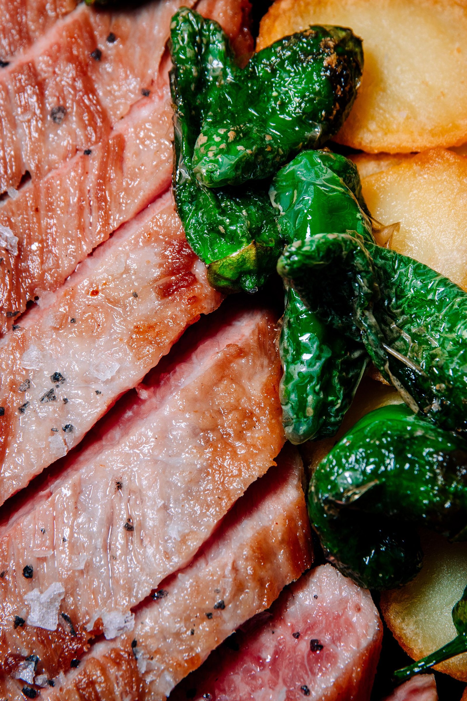 Piezas de carne con patatas y guarnición verde.