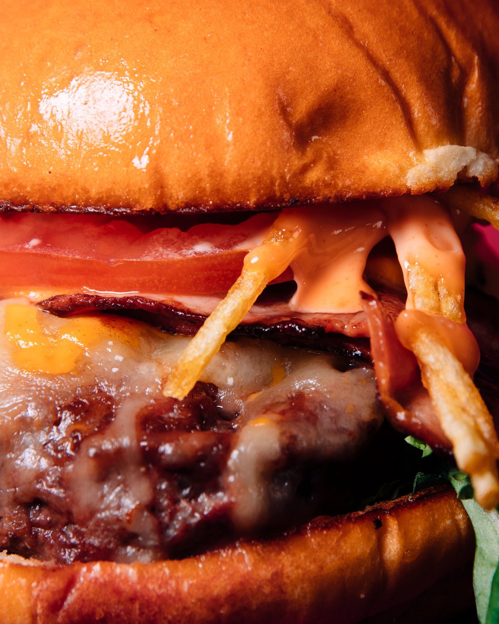 Primer plano del interior de una hamburguesa con queso y salsa.